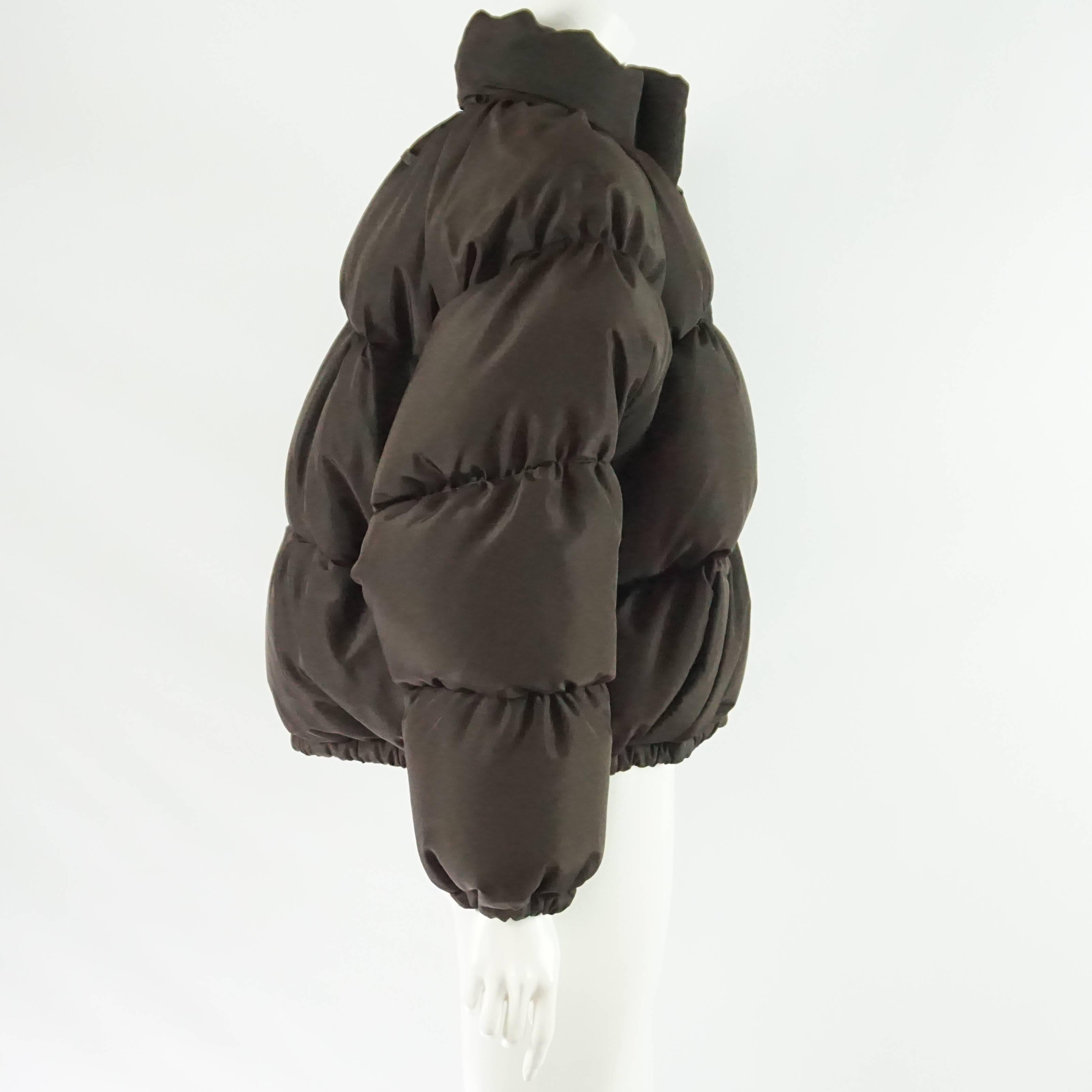 This Jean Paul Gaultier dark brown oversize puffer jacket has a detachable hood and a front zipper with 2 front pockets. The jacket is in excellent condition with minimal wear. It is a size M but can also fit a L due to its size. Circa