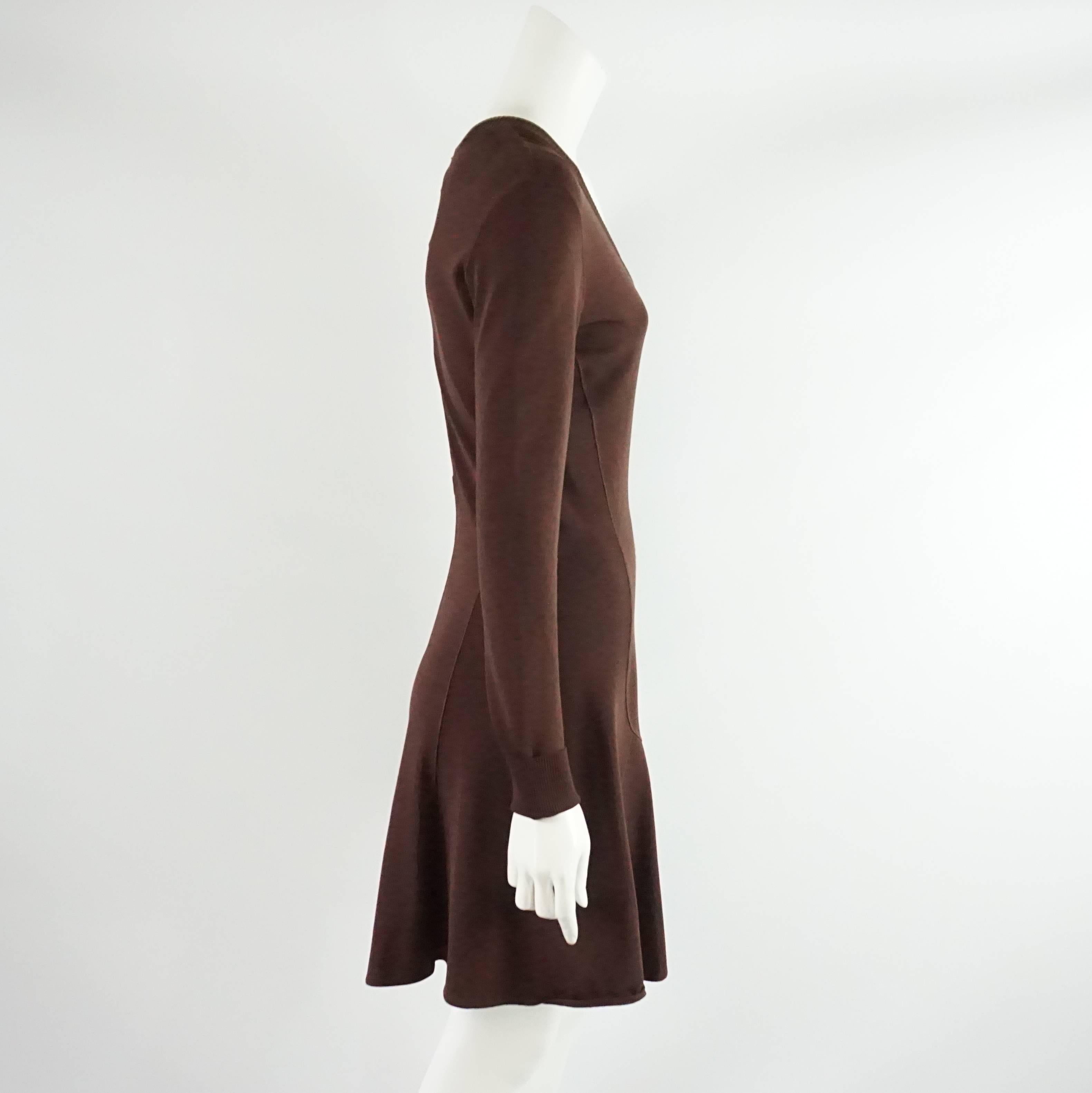 This Alaia brown knitted dress is made of a thick synthetic fabric. It has a tapered fit with a v-neck, flowing skirt, and back zipper. The piece is in good vintage condition with minor wear to the fabric and some pilling as seen in the images.