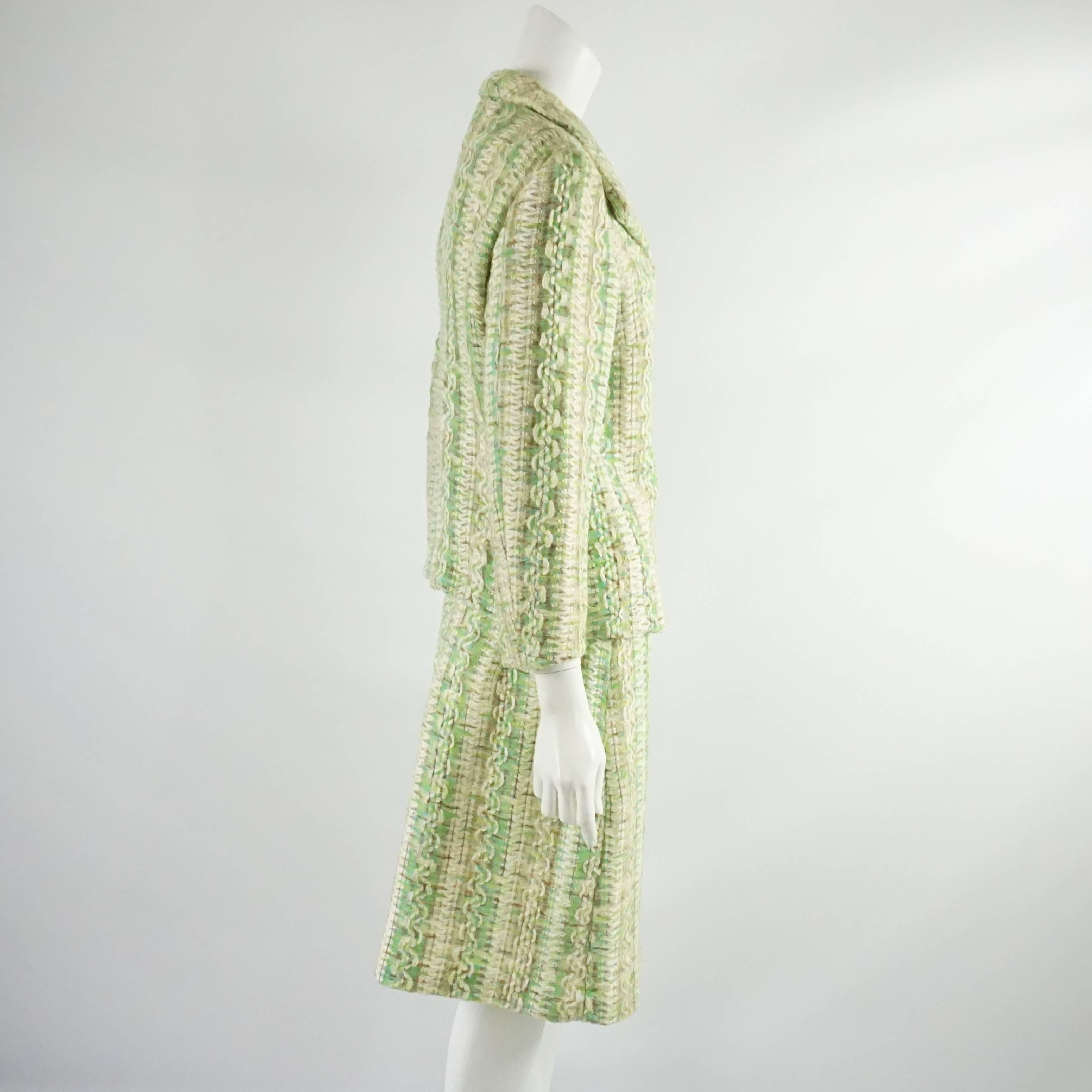 Ce tailleur jupe vintage Bill Blass des années 1980 présente un motif texturé de vert, d'aqua, de blanc et de marron. La veste est munie de trois boutons d'aspect tissé argenté avec un bord doré. Ce tailleur jupe est entièrement doublé et en très