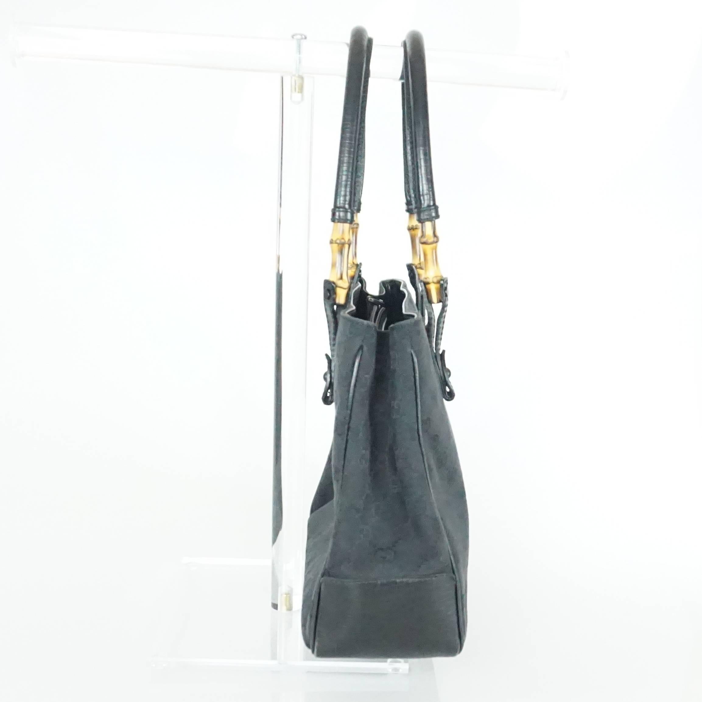 This beautiful Gucci black monogram shoulder bag has small bamboo detailing on the straps. Inside, there is a zipper compartment and two open compartments. It is in excellent condition with minor wear on the bottom and a duster is
