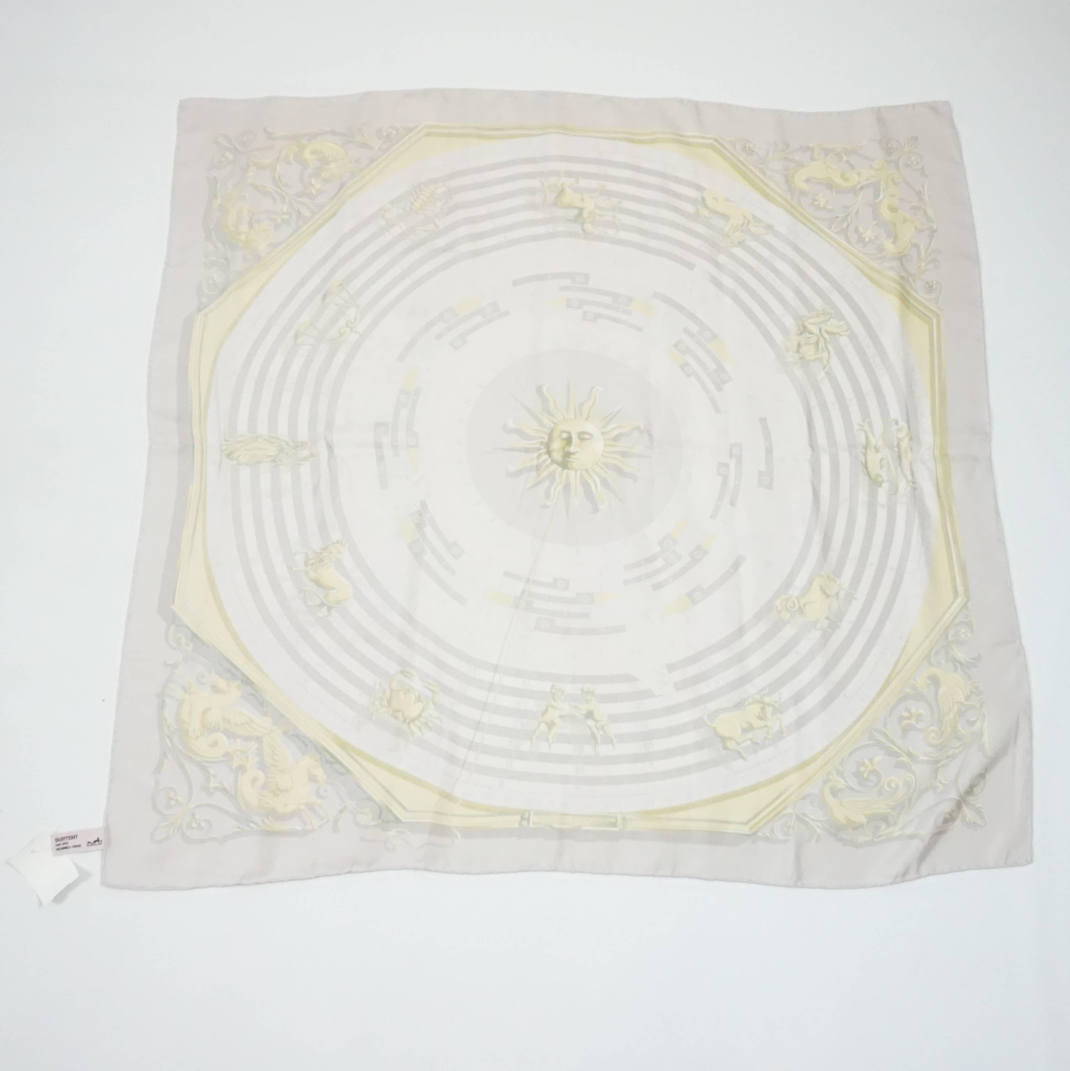 This Hermes scarf is a light, pale lavender with a golden astrology and sun print. The title is 