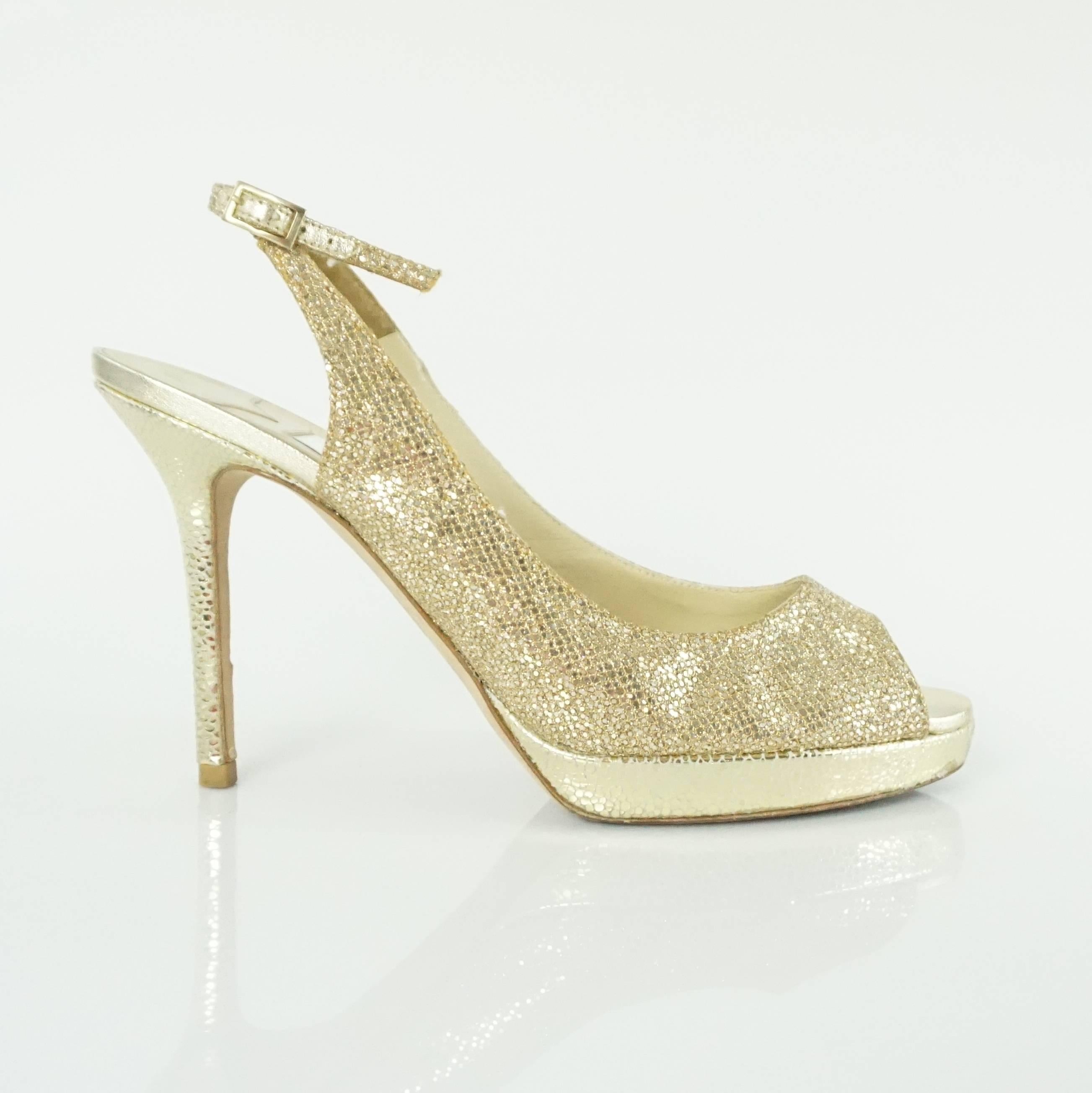 These Jimmy Choo gold glitter slingbacks are a truly glam pair of shoes. They feature a peep toe, gold glitter body, cracked gold leather trim, and adjustable slingback strap. They are in very good condition with some wear to the back and slights