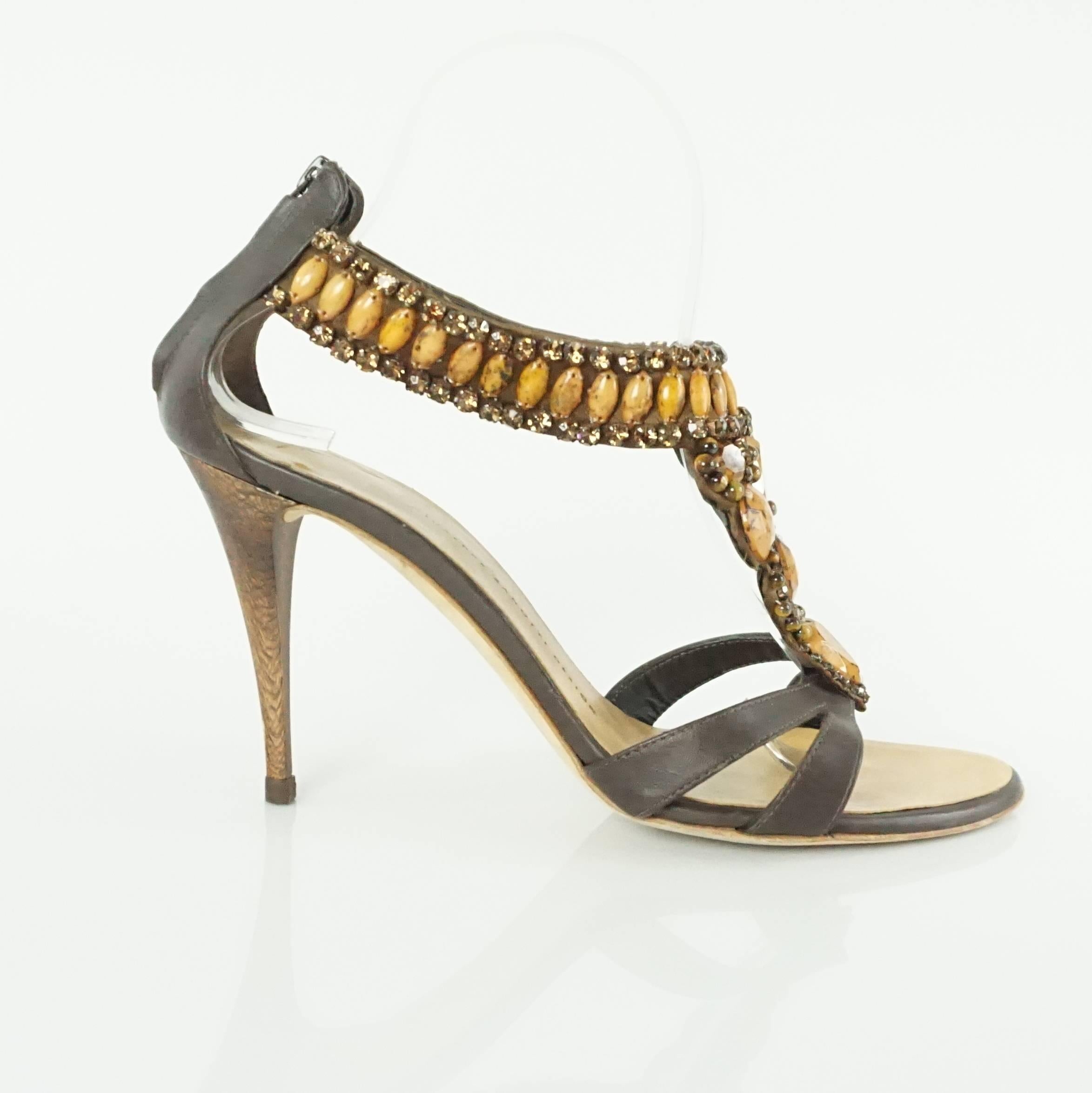 These Giuseppe Zanotti heeled sandals are a unique, stunning shoe. They feature caramel stones and bronze rhinestones, brown leather, an open toe, and a back zip at the ankle strap. They are in very good condition with some wear on the bottom, the