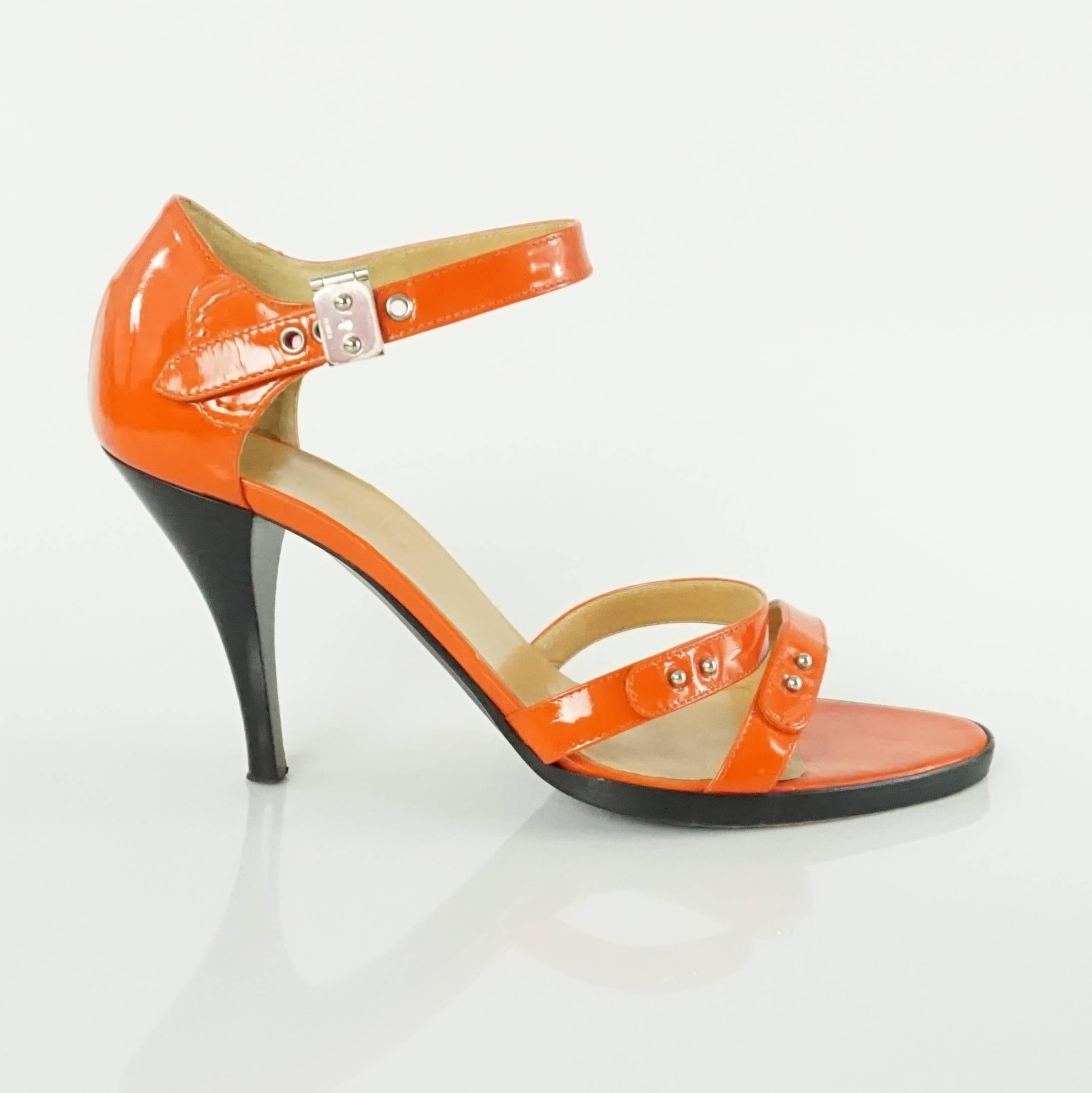 These Hermes orange patent heeled sandals are a fun pop of color. They have double straps in the front and an ankle strap with a silver Hermes signature closure. They are in very good condition with some wear at the ankle strap and bottom as seen in