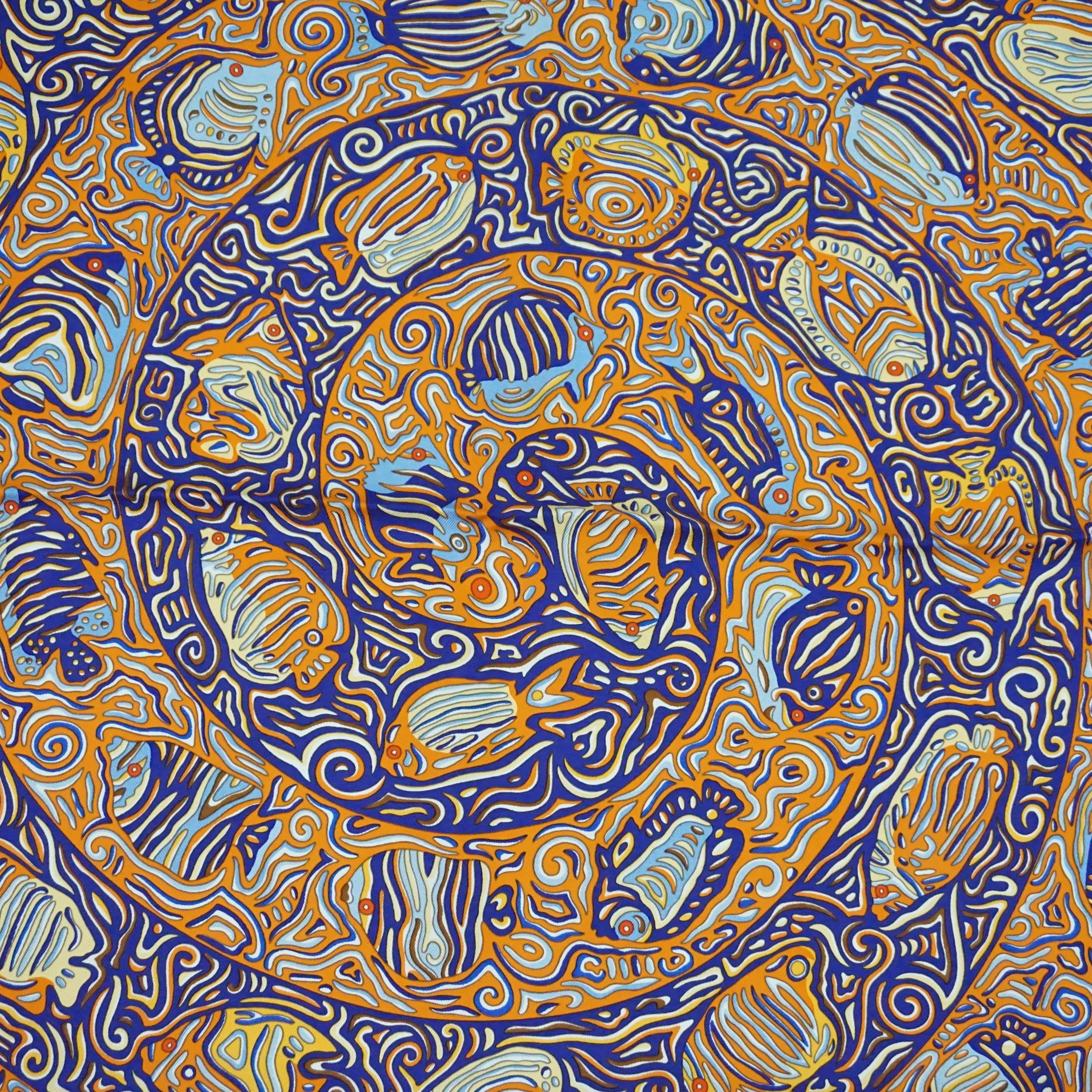 This Hermes silk scarf has an aquatic mosaic theme with different hues of blue, orange, and yellow. It is by Christine Henry and is titled, 