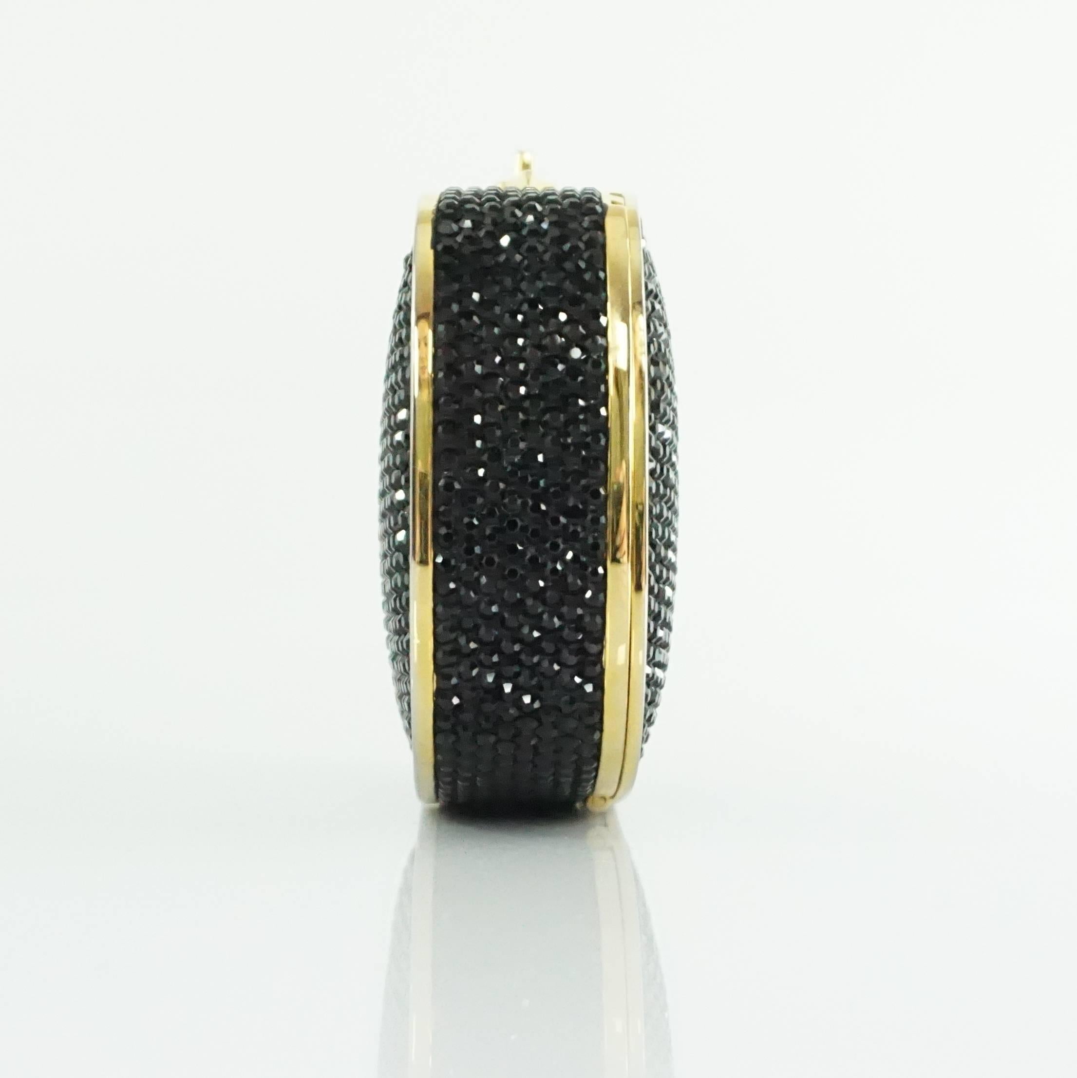 This beautiful Judith Leiber black rhinestone minaudiere has a gold strap that can be tucked inside. There is a gold trim and closure. This bag is in excellent condition.

Measurements
Width: 3.75"
Length: 4.8"
Depth: 1.2"
Handle
