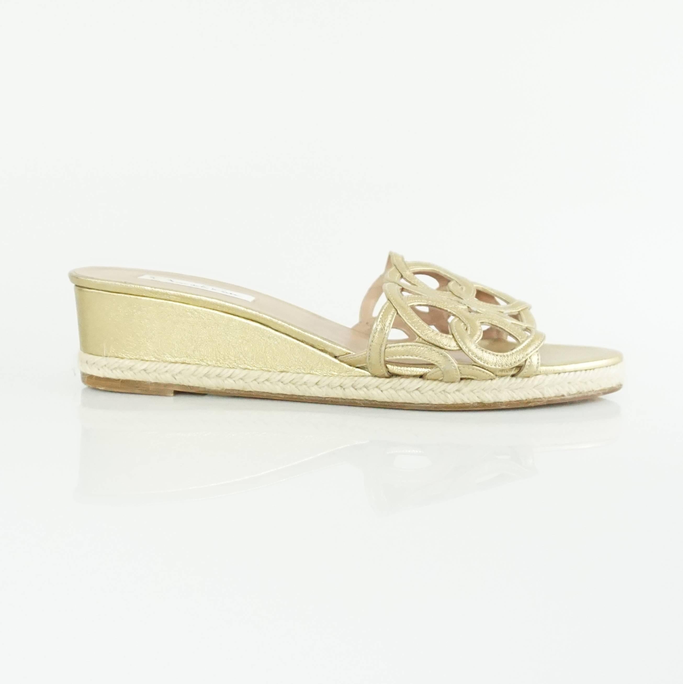 These Oscar de la Renta low wedges have a gold cutout strap. There is a braided rope trim and the shoes are a metallic gold. They are in very good condition with minor bottom wear and minor scuffing on the strap.

Measurements
Wedge Height: