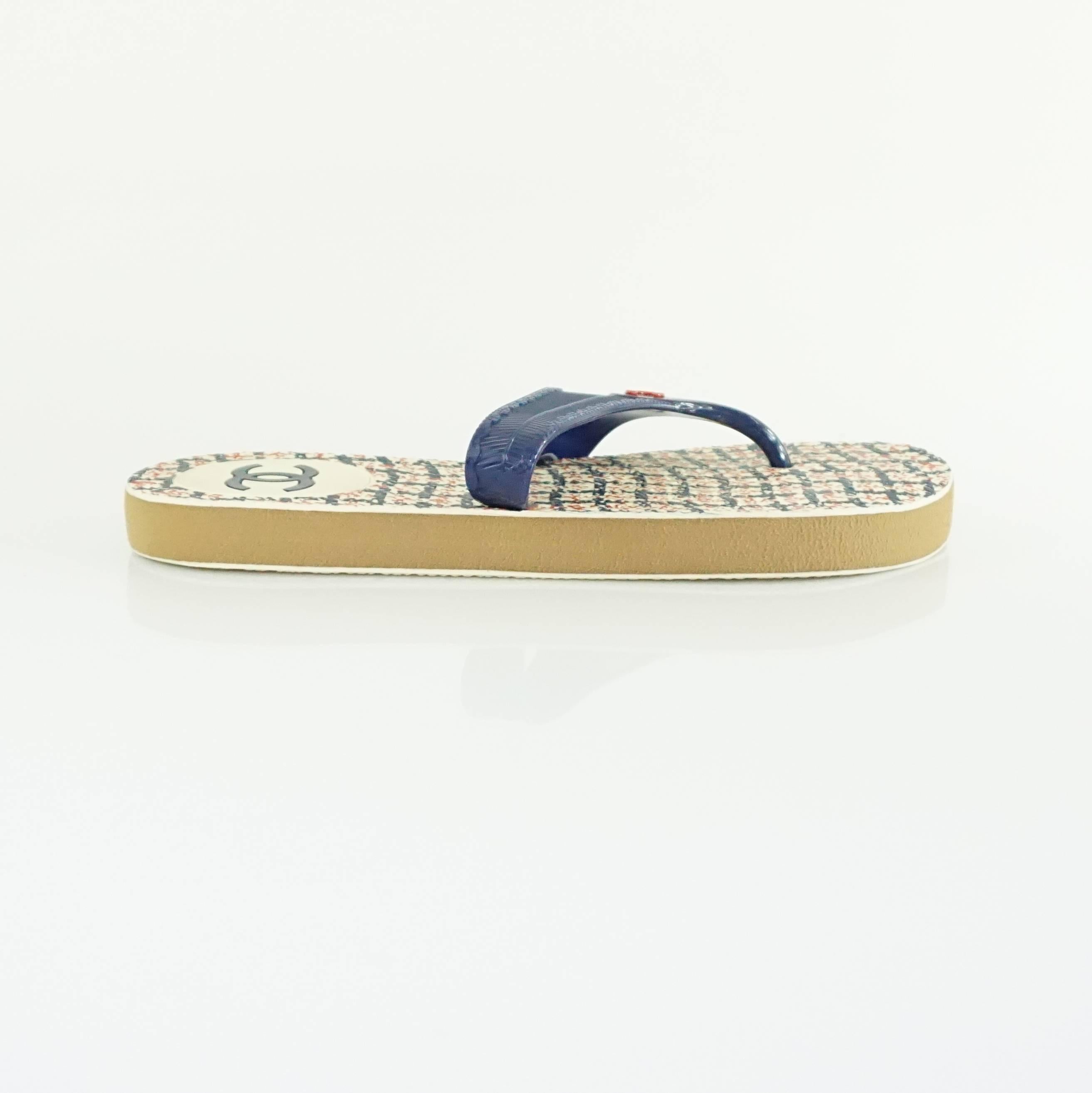 These Chanel rubber thong sandals are navy and red. On the strap, there is a red Chanel logo. They are in excellent condition.

Measurement
Platform height: .75"