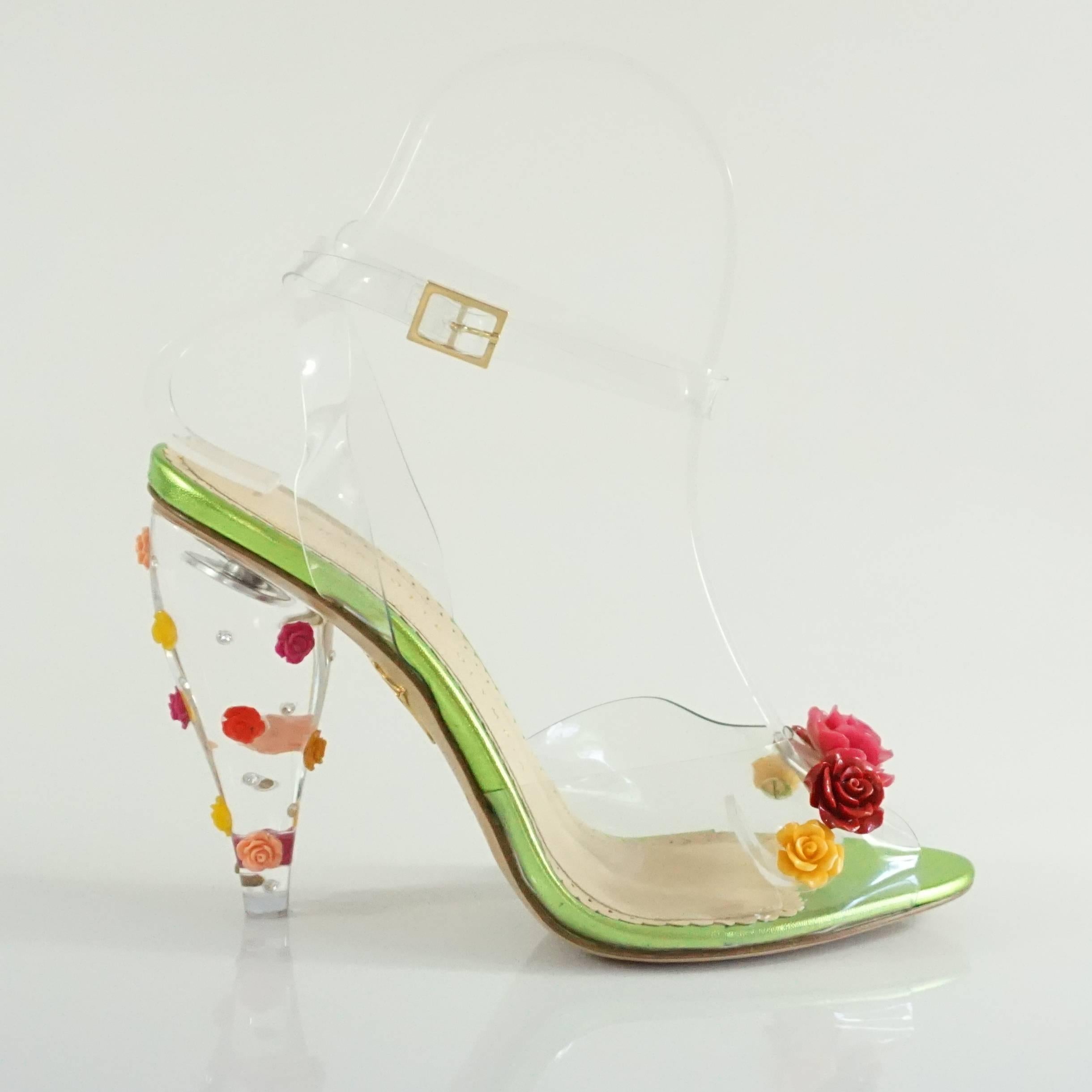 These Charlotte Olympia heels have a clear heel, strap and toe band. They flowers of different colors are the toe band and lucite heels. The heels also feature rhinestones. These shoes are in new condition with a scuff on the side of one of the