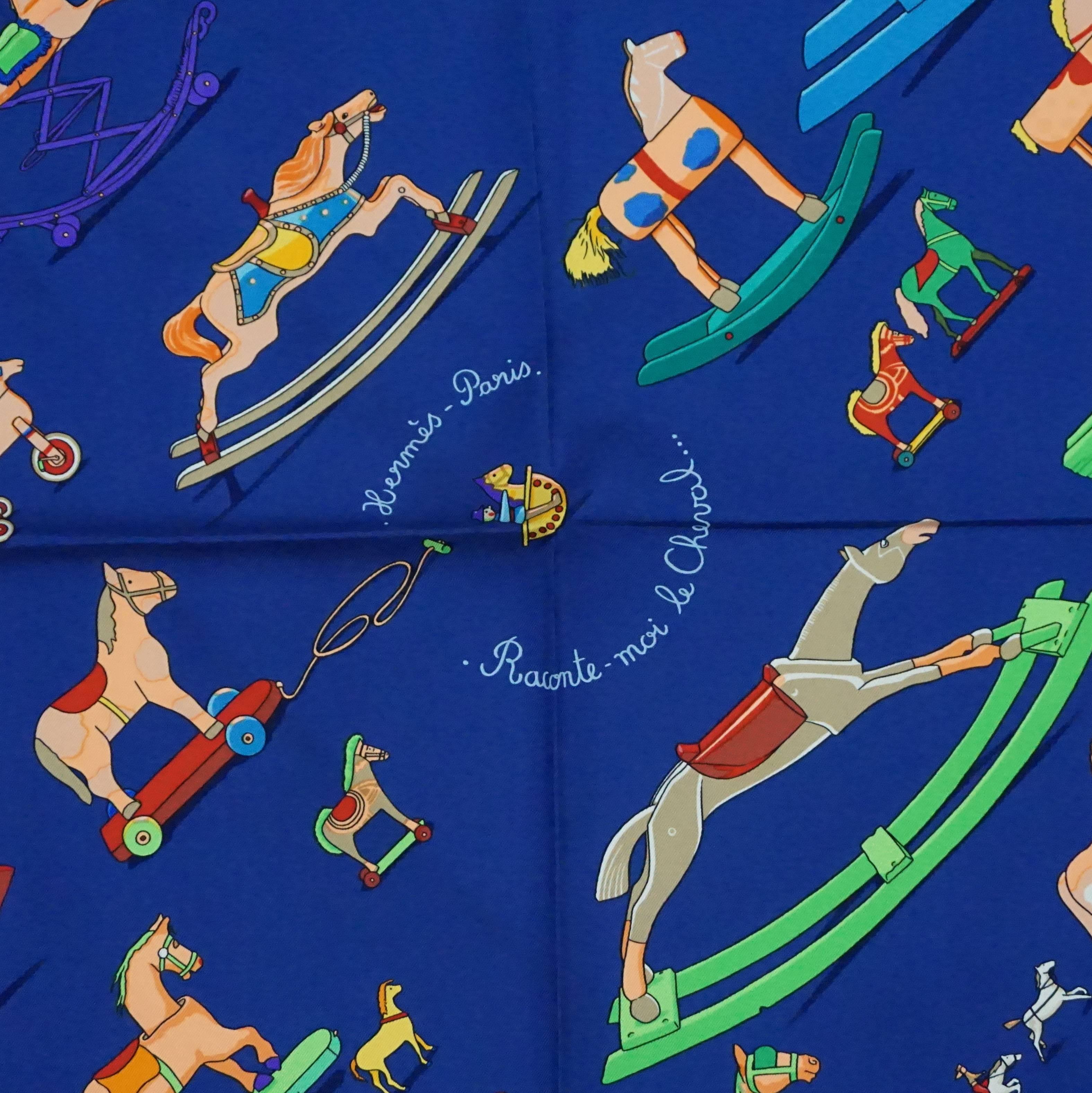 This beautiful Hermes silk scarf is blue with a multicolored rocking horse design. There is a red and blue trim. This scarf is in excellent condition.

Measurements
Length: 35" 
Width: 35.5"