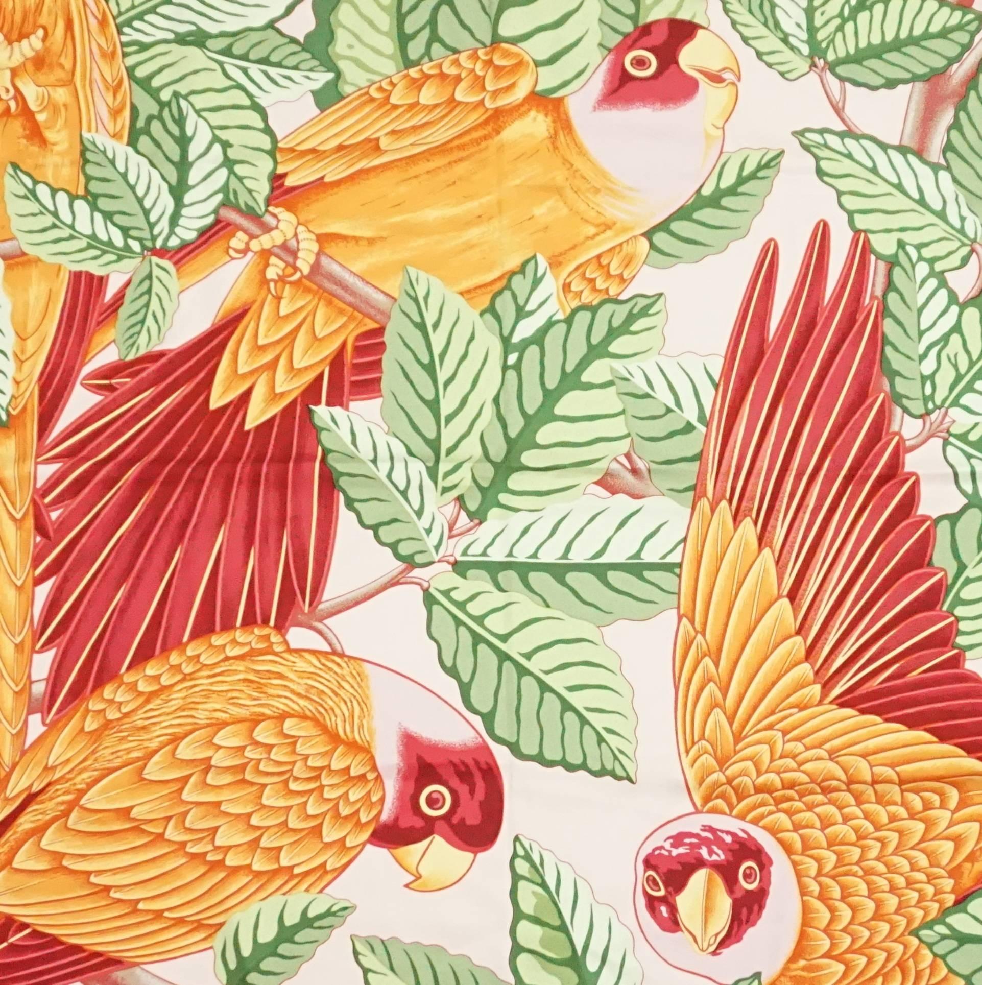 This Hermes scarf has a vibrant pink trim and a parrot design. The design has green leaves and orange and red parrots. This scarf is in excellent condition.

Measurements
Length: 35"
Width: 35.5"