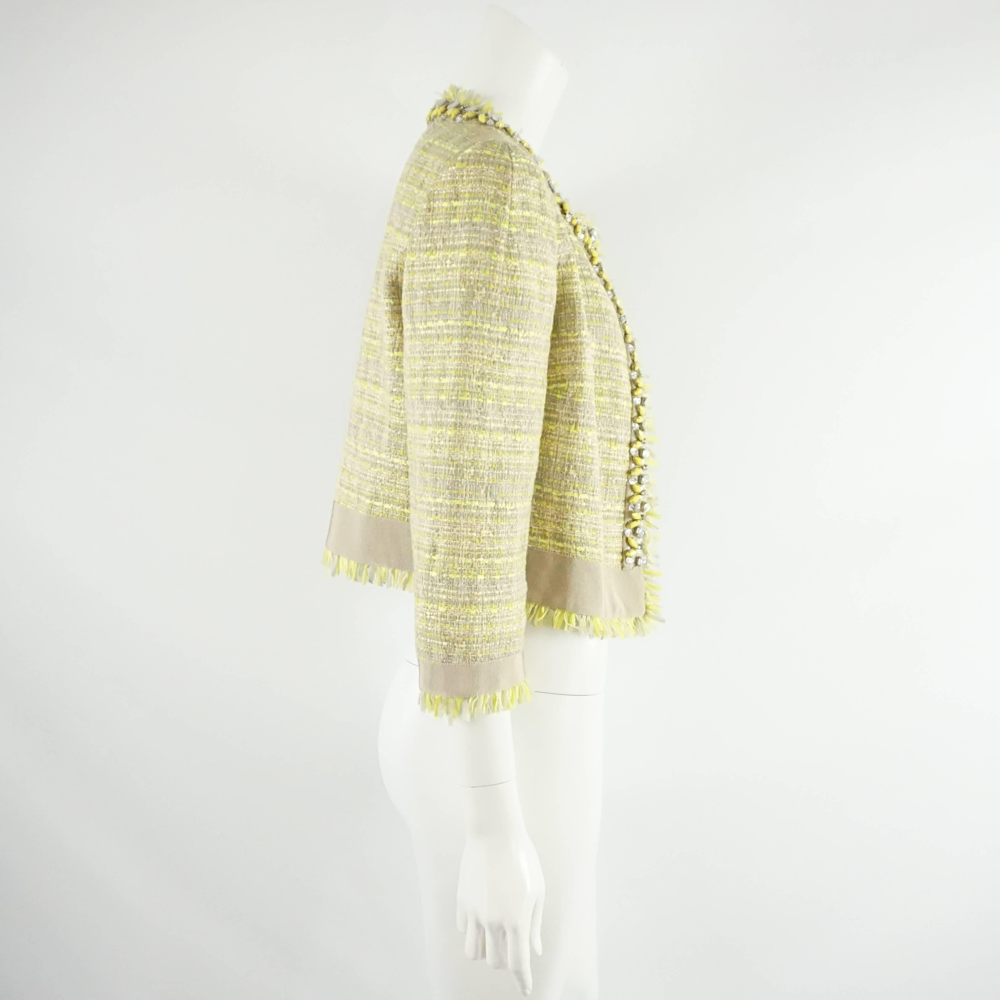 Diese Jacke von Giambattista Valli besteht aus einem taupefarbenen und gelben Tweed-Stoff, der aus einer synthetischen Mischung besteht. Die Jacke hat außerdem ein taupefarbenes Ripsband am unteren Rand, gelbe und durchsichtige Strasssteine und