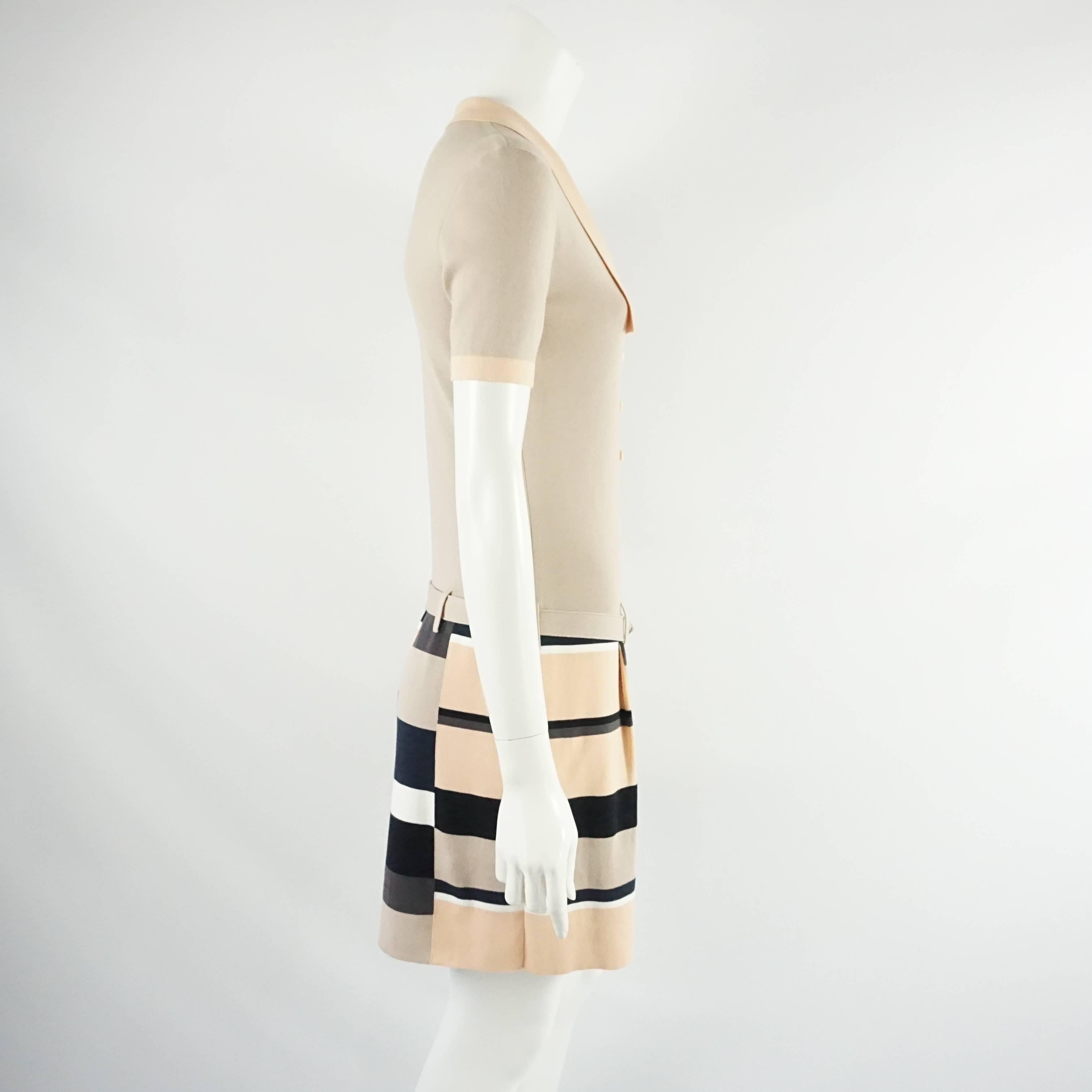 This Fendi cotton knit dress is light taupe with peach trim on the collar and neckline. The skirt has slight pleating and a taupe, peach, black, and brown checkered print. The dress also comes with a cotton belt that has the silver Fendi classic