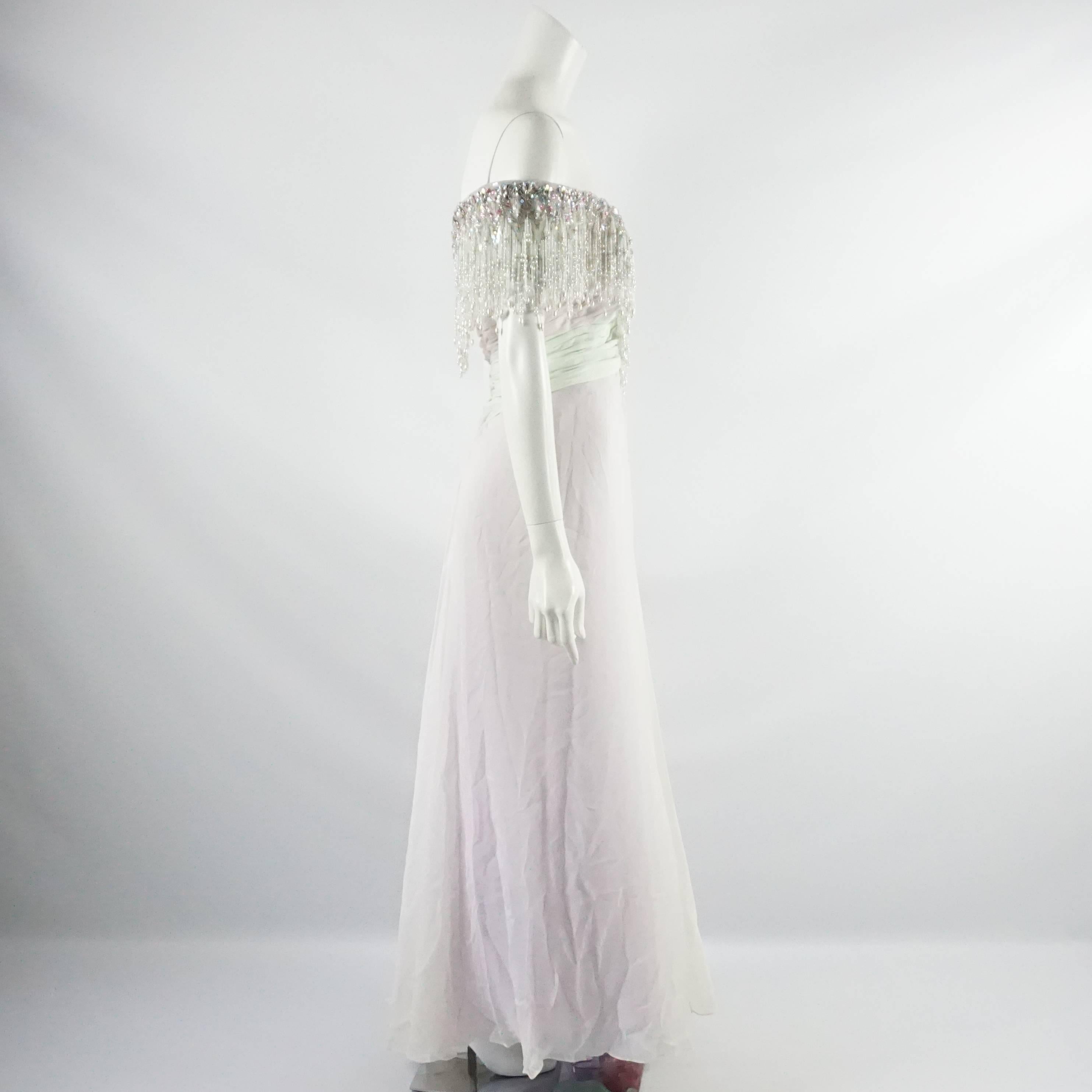 This vintage 1980's Bob Mackie gown has a whimsical feel. This gown is silk chiffon and pastel green, pink, and purple. It has an off-shoulder design, hanging beading, a fitted bodice and a flowing and loose skirt. This gown is in very good vintage