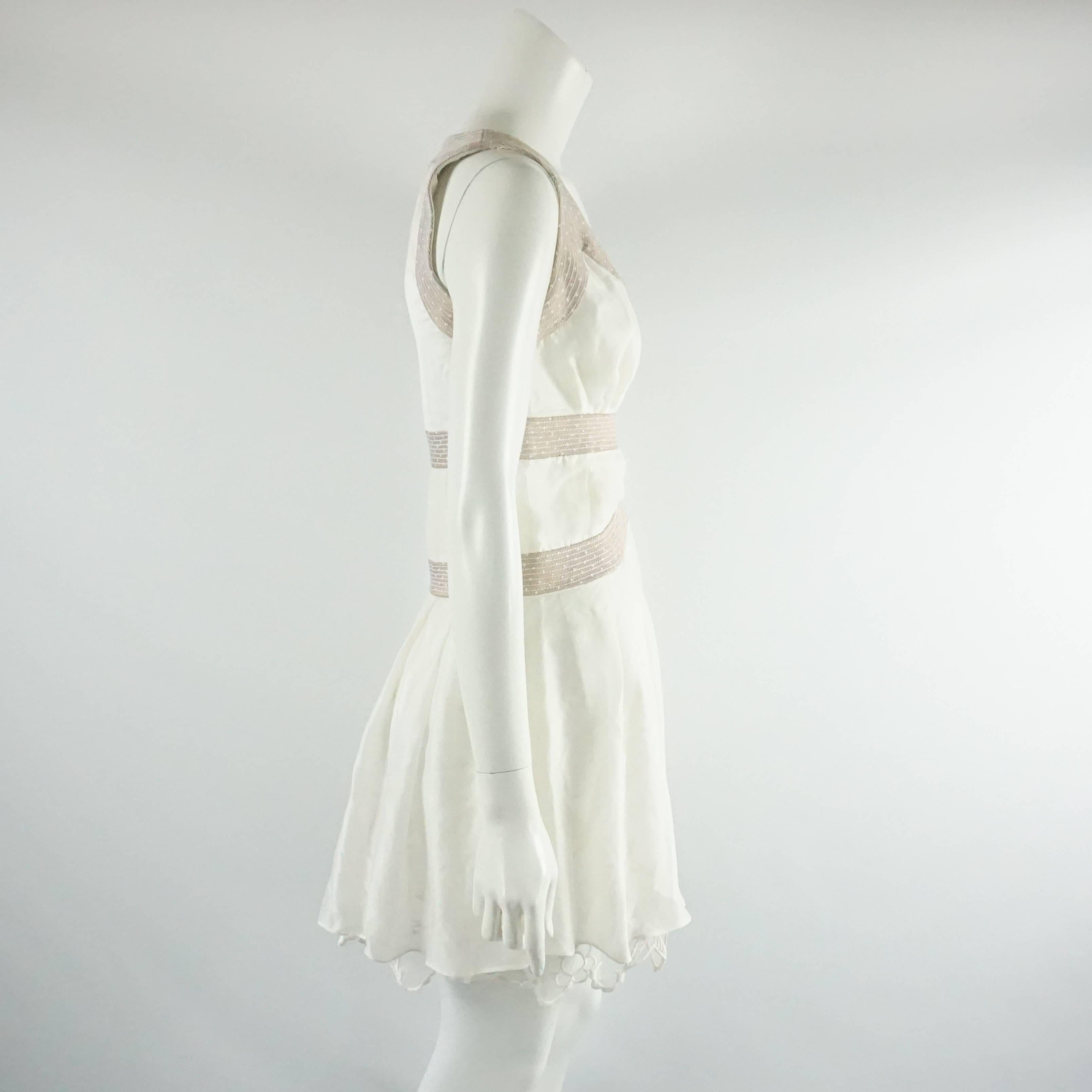 This Nina Ricci ivory dress has a thick lace underpinning with a sheer cotton overlay. The dress also has a copper metallic stitched design along the bodice, flowy style, and a side zipper. The dress is in very good vintage condition with light wear