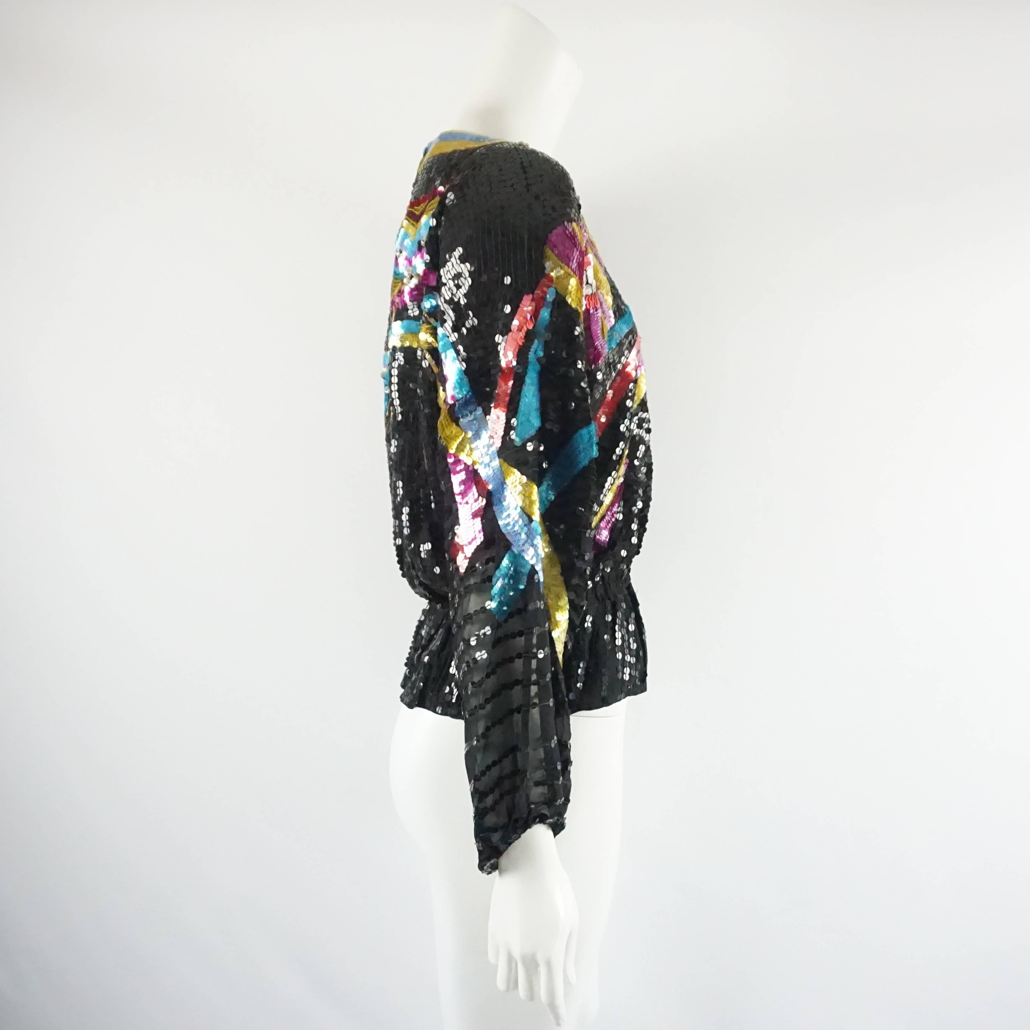 The beautiful Neil Bieff blouse from the 1970's and is black with a multi-colored masquerade theme design. It is covered in sequins and has loose sleeves. There is a cinching along the bottom and then the blouse flares out. The sleeves are sheer.