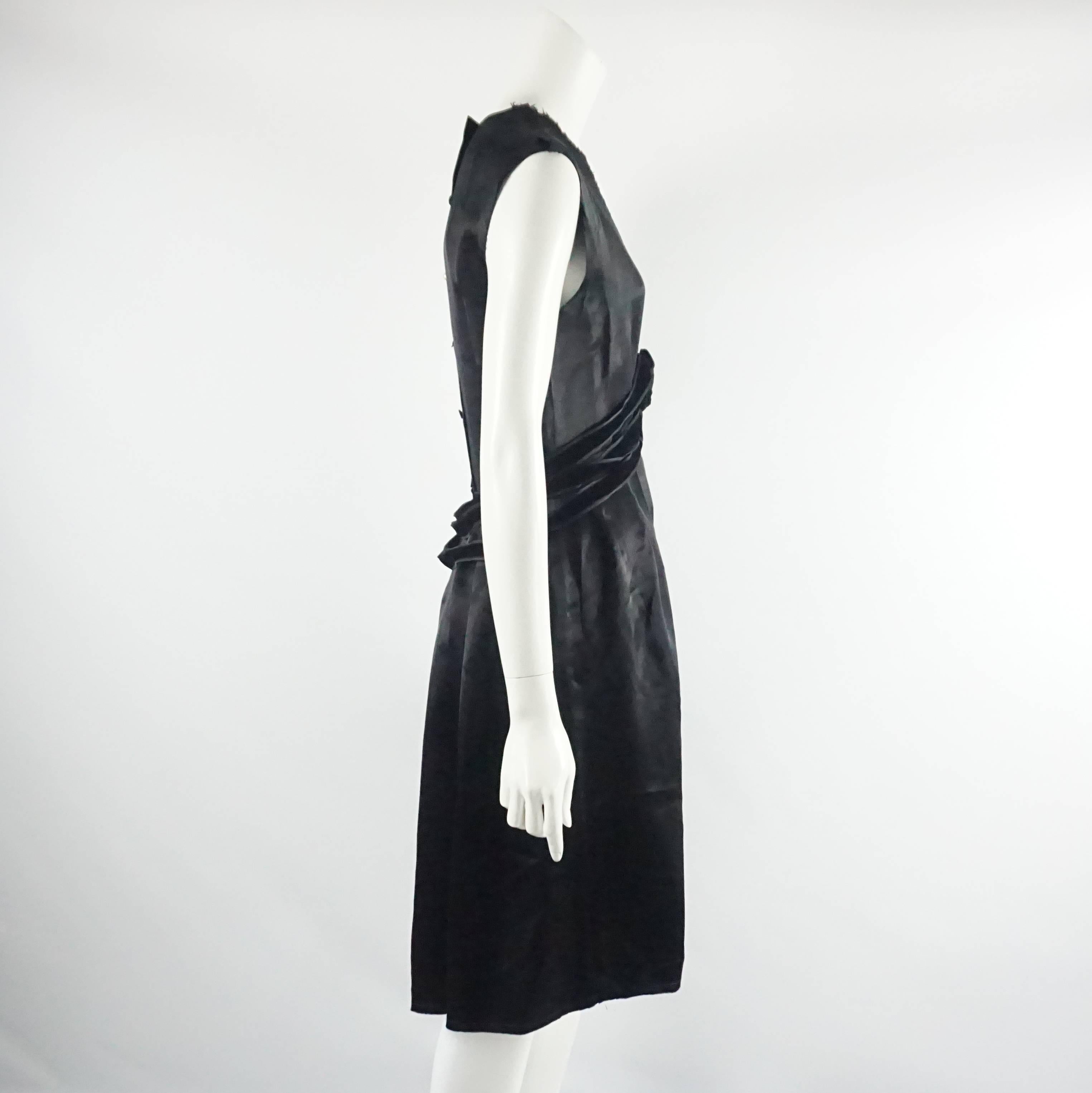 This Lanvin black sleeveless dress is made of silk. It has a deep v-neck with velvet waist ribbons, a center ruched rose, and a button up back. The dress is in excellent condition with light wear. 

Measurements
Bust: 34.5"
Waist: