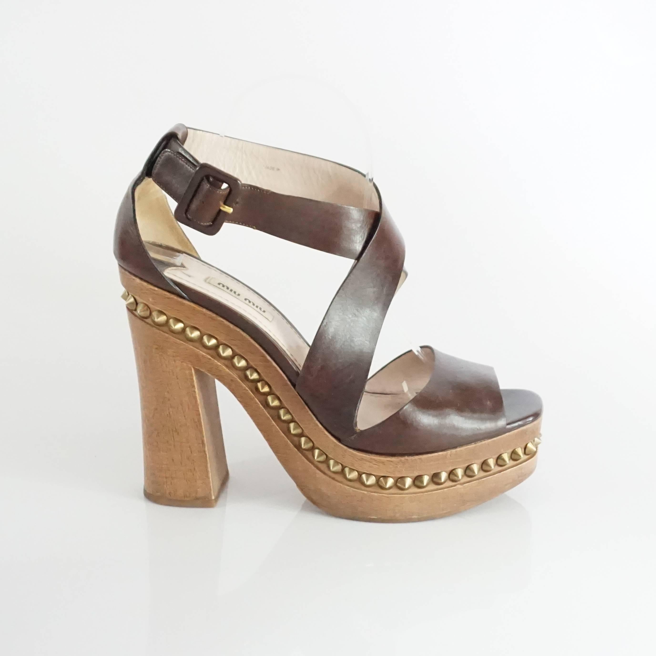 These Miu Miu heels have a strappy brown leather design. There is a wooden platform and wooden chunky heel with flat gold spikes. The shoes are in fair condition and have wear on the wood and leather (all shown in the last images). Size 41. 

Heel