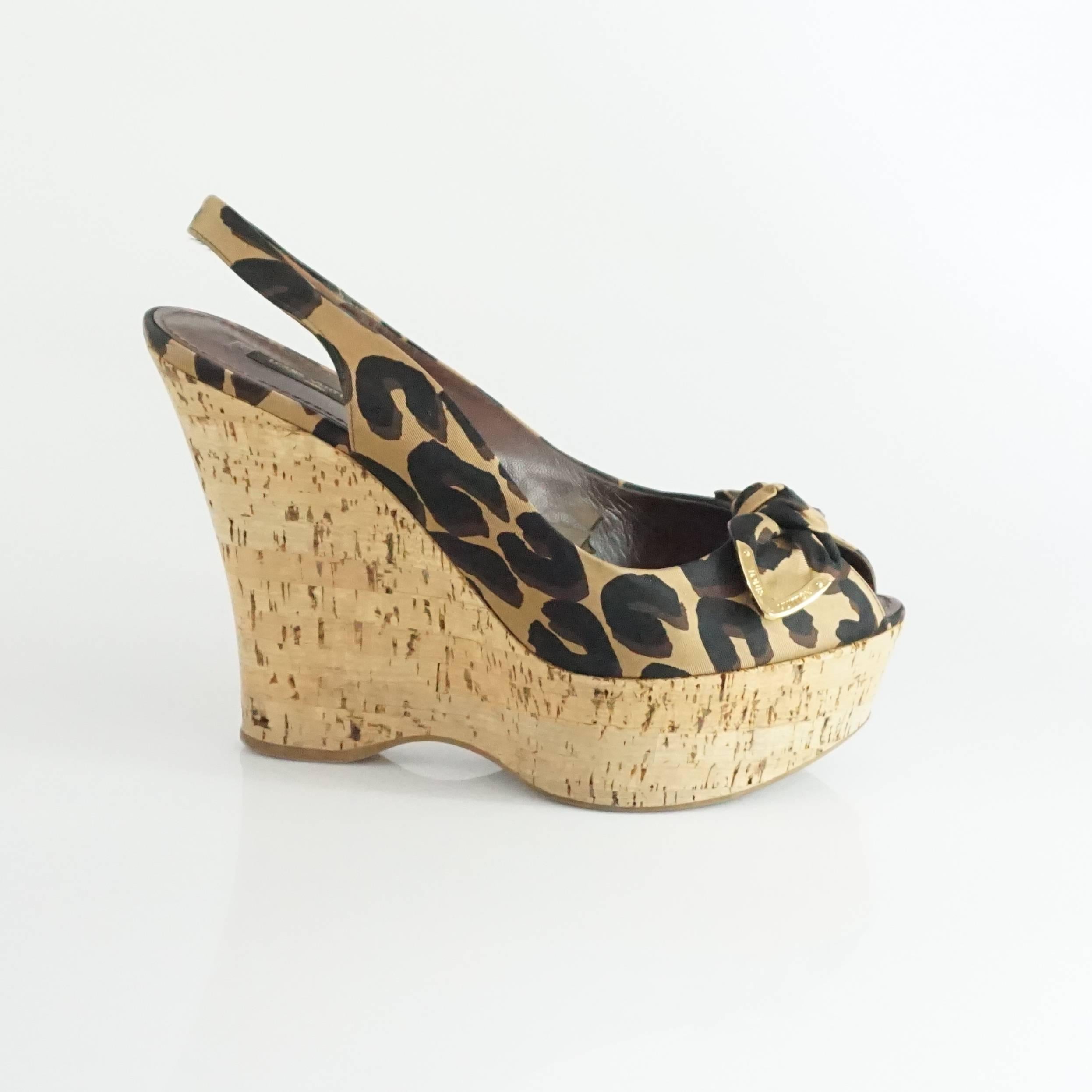 These Louis Vuitton wedges are animal print and are made of satin. They are slingback style with a front bow, cork heel, and peep-toe. They are in very good condition with minor wear on the bottom and in one area inside as shown in the image. Size