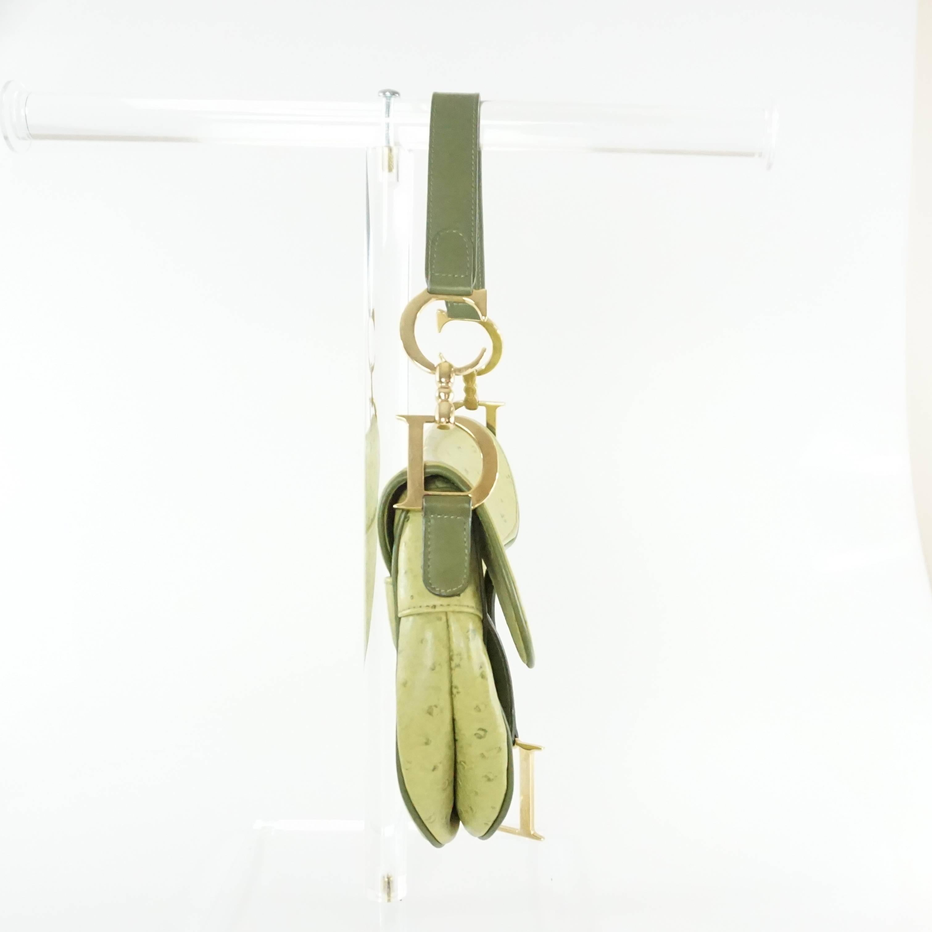 This Christian Dior green ostrich saddle bag is the perfect pop of color! It has an asymmetrical shape with gold 