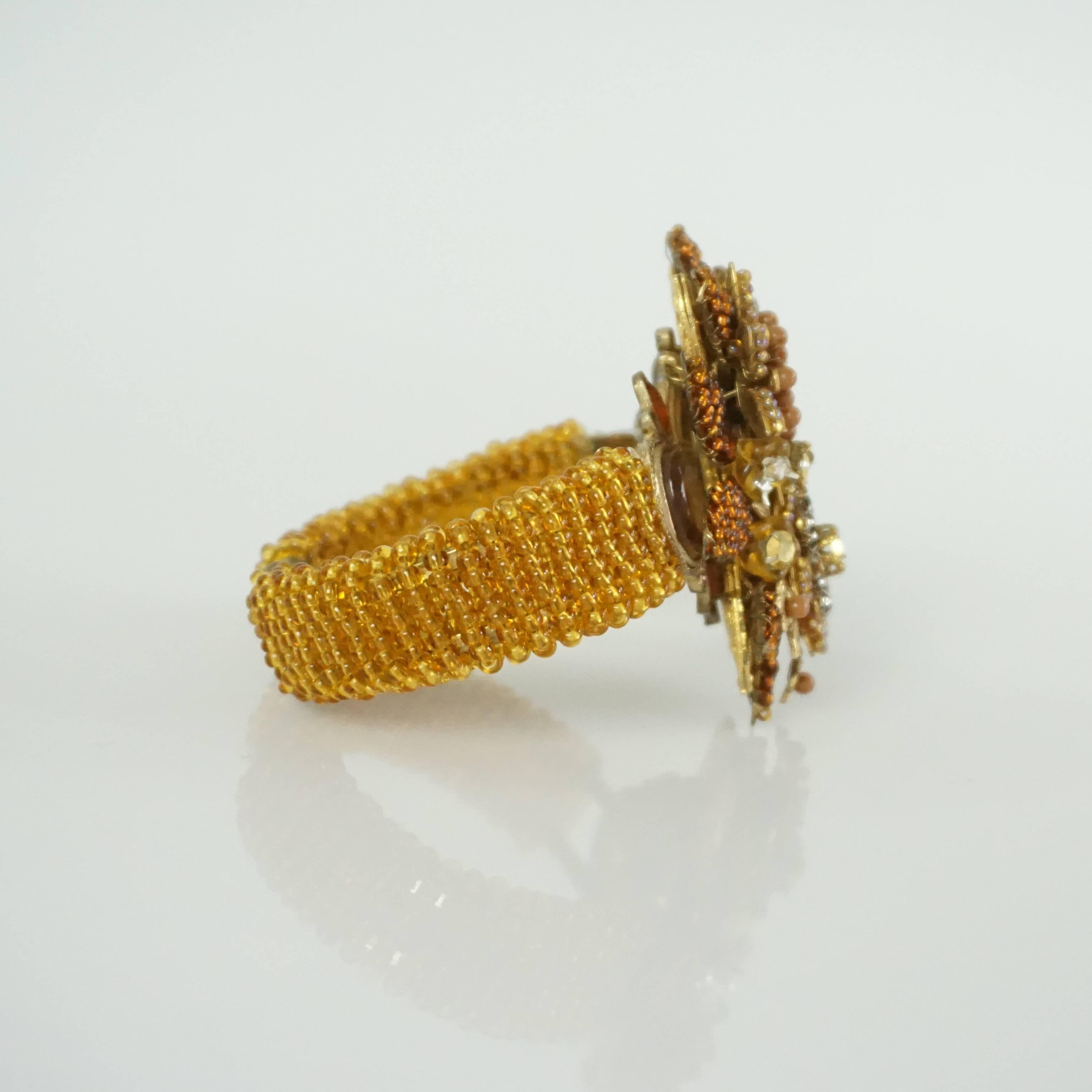 This Stanley Hagler bracelet has beads in an amber color creating a floral design. The band is covered in beads also. This bracelet is in excellent condition with discoloration on the inner metal. 

Measurements
Width of band: 0.75