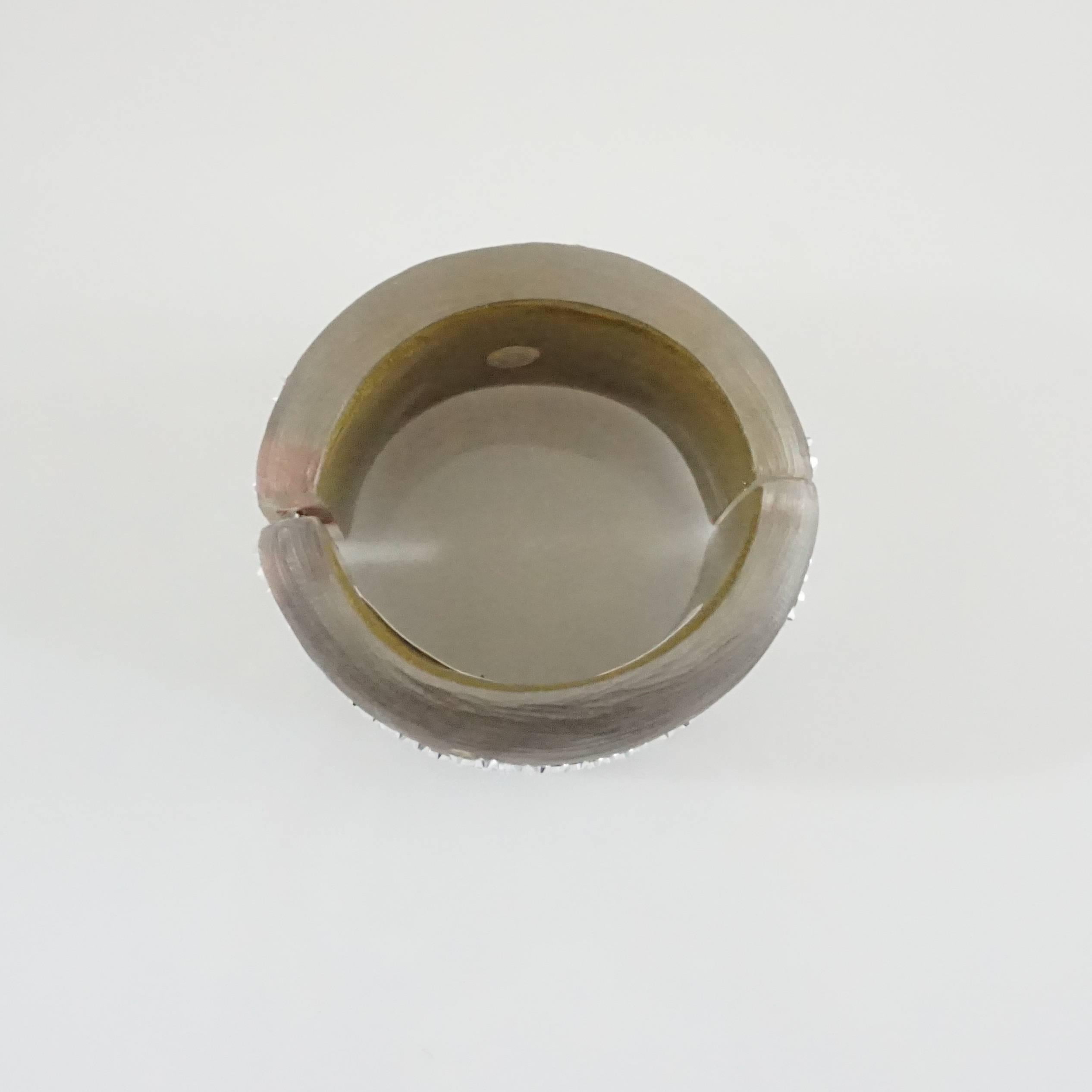 This Alexis Bittar enamel cuff is taupe with rhinestones. The cuff has a hinge that allows the cuff to be opened. This cuff is in very good condition with some missing rhinestones.

Measurements
Width: 2
