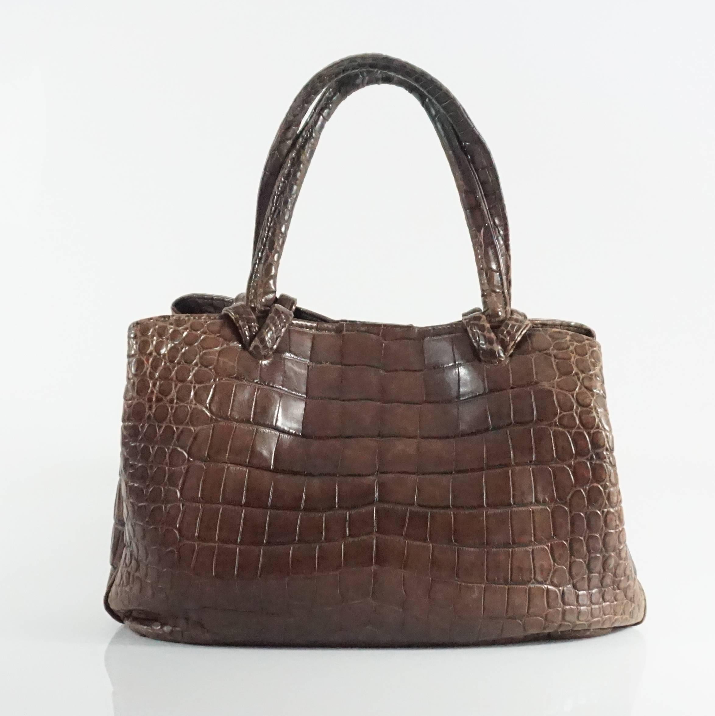 This Giorgio's brown alligator bag is a staple piece that has a long crossbody strap. It has a more slouchy style with three open compartments and two zipper compartments The bag also has 2 sets of credit card slots and a small compartment on the