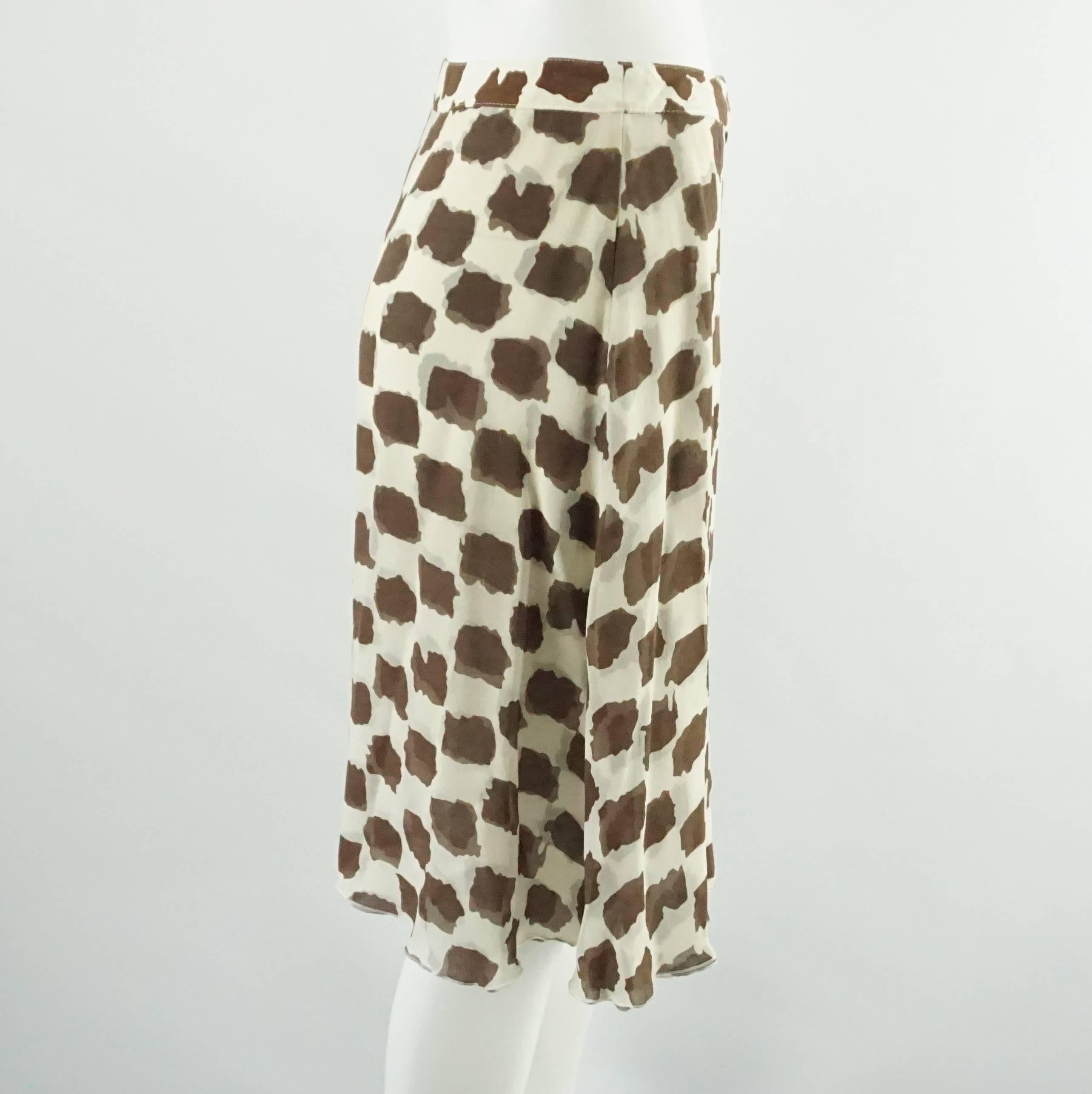 This Valentino brown and ivory printed skirt is made of silk chiffon. It has several layers of fabric, tortoise buttons going down the front, and a tortoise belt buckle and closure. The skirt is in fair vintage condition with a couple blemishes as