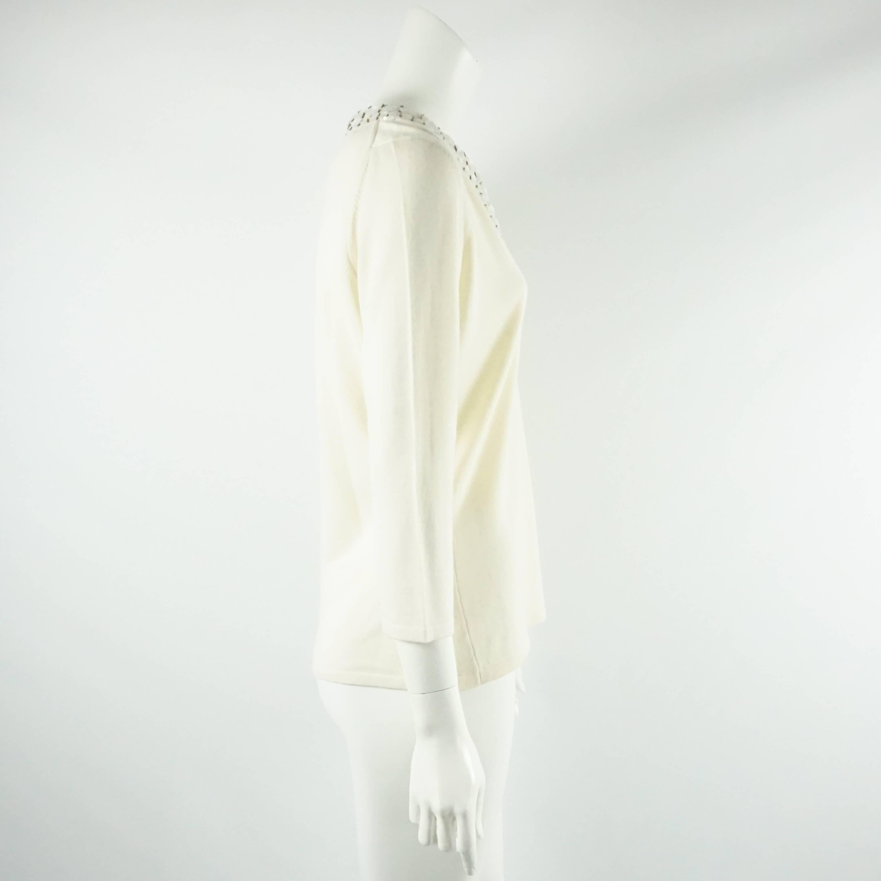 This Oscar de la Renta cashmere and silk blend sweater is ivory with stones, beads detailing around the neckline. It has a v-shape neckline and closures to close the neckline. This sweater is in excellent condition.

Measurements
Shoulder to