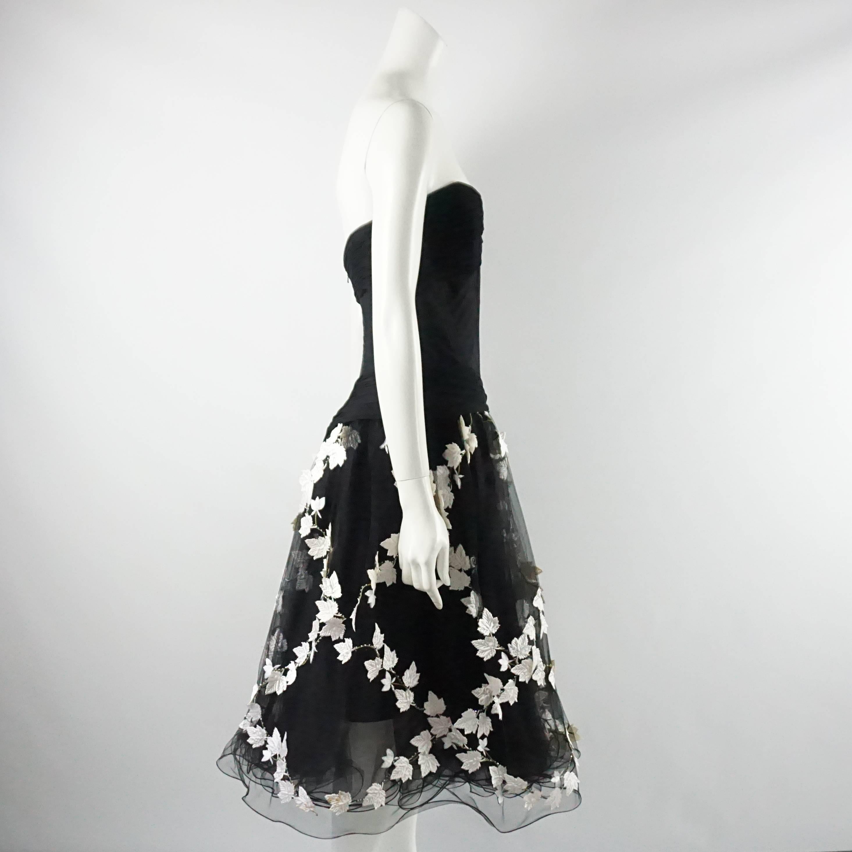 This Vicky Tiel dress looks fantastic on. The bodice is made of mesh and has boning with a back zipper closure. The skirt has layers of tulle with white leaf appliqués and sequin detailing. It is in excellent vintage condition with minimal wear.
