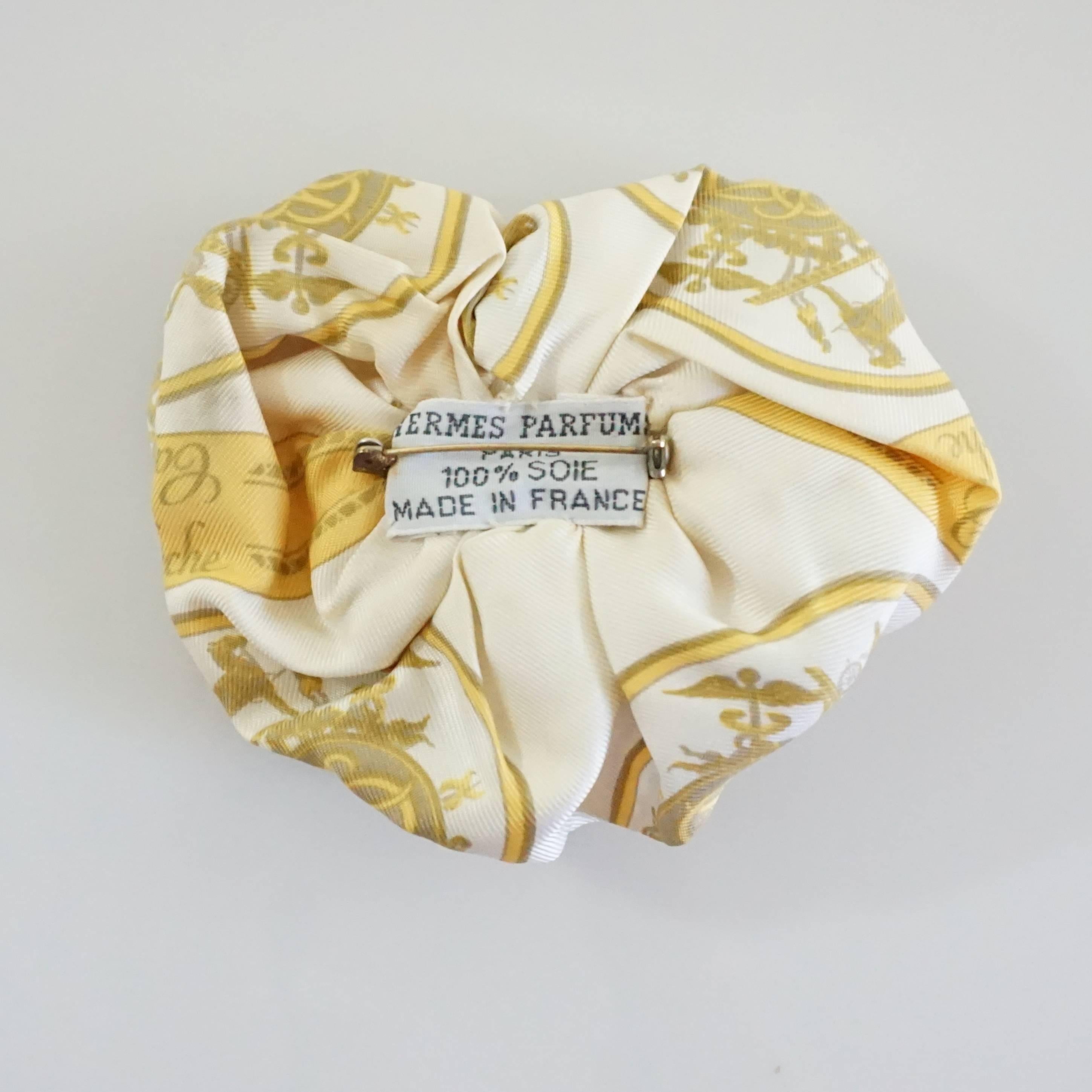This Hermes brooch has a carriage print with ivory, gold, and tan colors. The fabric is silk and it is ruched to look like a camellia. It is in excellent vintage with minimal wear. 

Measurements
Height: 4