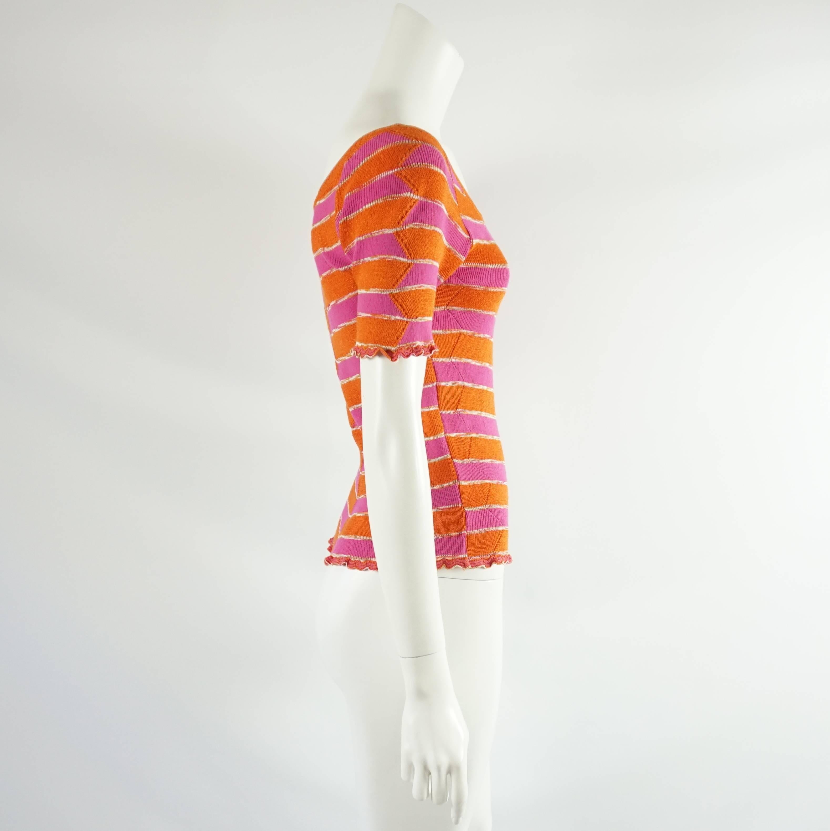 This Missoni knitted top is short sleeved with a v-neck. There are orange and pink stripes with white detailing. There is a small scallop trim on the sleeves and shirt hem. This shirt is in excellent condition. Size small.

Measurements
Sleeve