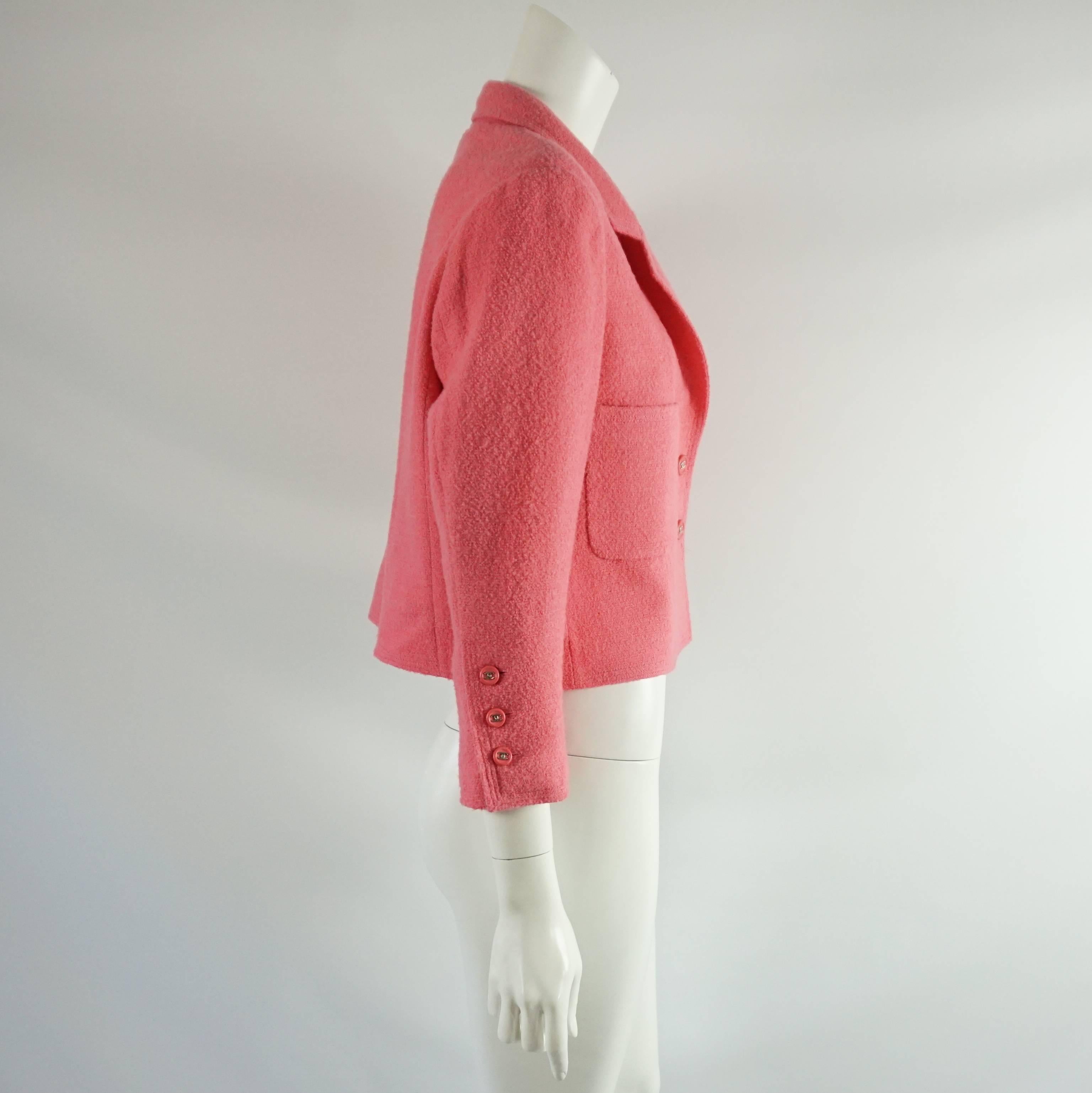 This beautiful Chanel cropped jacket is pink wool. There are 2 large pockets on the front. The buttons are pink with a silver Chanel logo and there are 2 buttons on the front and 3 on each sleeve. This jacket is in excellent condition. Size 8, circa