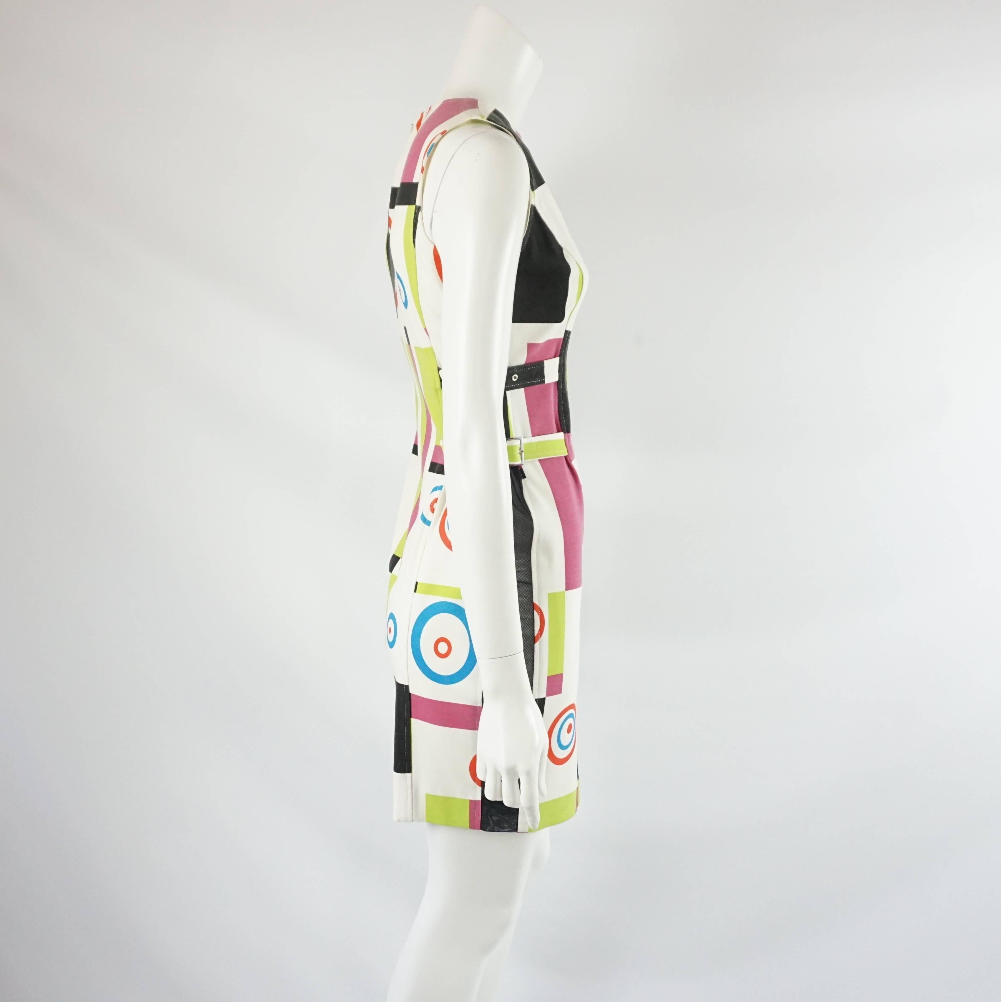 This Charles Jourdan dress is made of cotton and has a white and multi-color abstract print on it. The dress is sleeveless and tapered with mesh paneling on both sides and two small belts on each side. The dress is in very good vintage condition