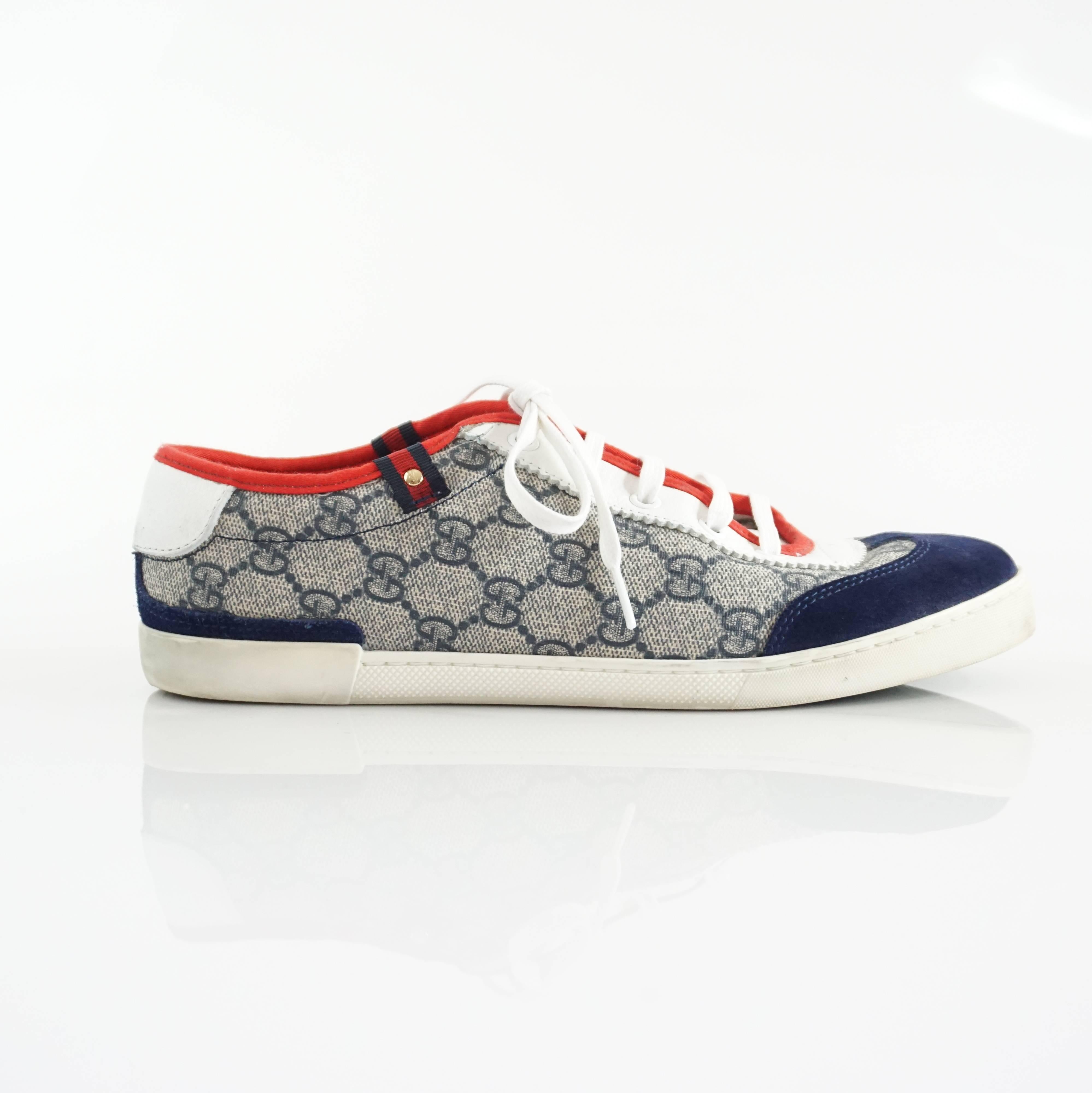 These Gucci sneakers are fabric with the Gucci monogram print in blue. There is blue suede-like detailing and a red trim. These sneakers are in good condition with overall staining and markings. Size 39.