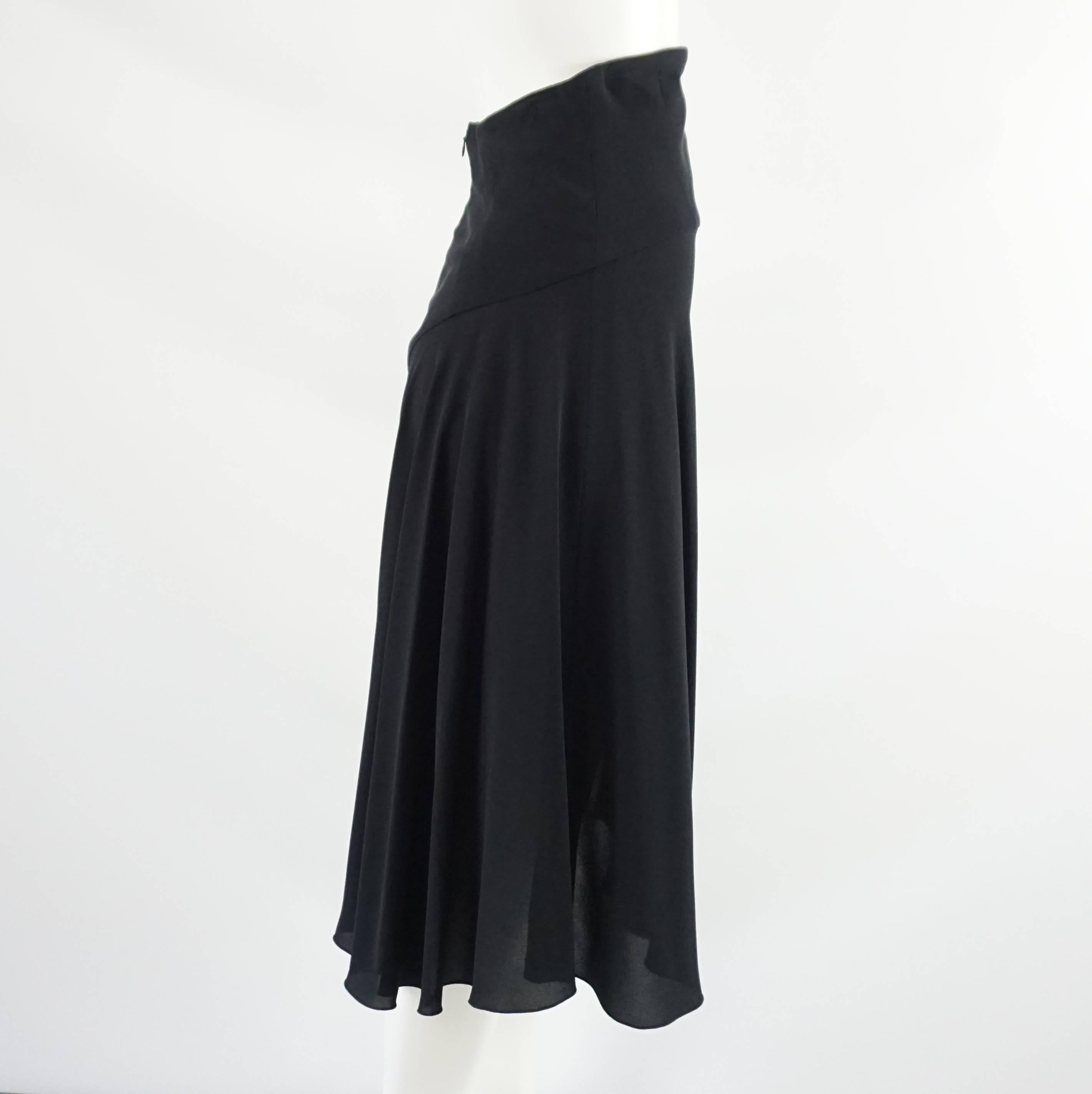This Chanel skirt has a long and flowing design. It is black silk with a high waist and asymmetrical hem. The first 6