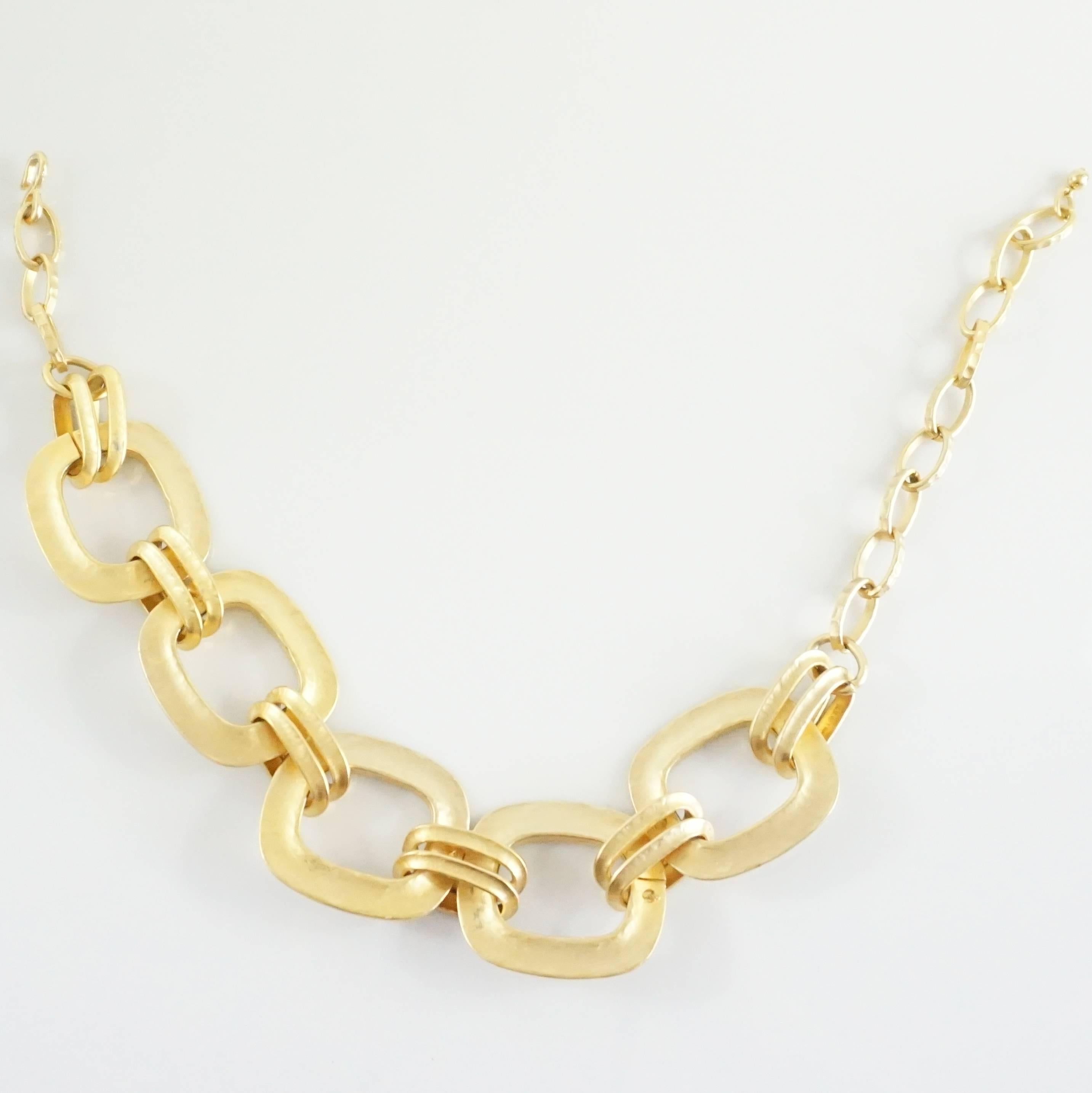 This KJL hammered gold necklace has large links in the front interlocking into smaller links towards the back. The clasp is a hook style with different options for length. The necklace is in excellent condition with minimal wear to the gold as seen