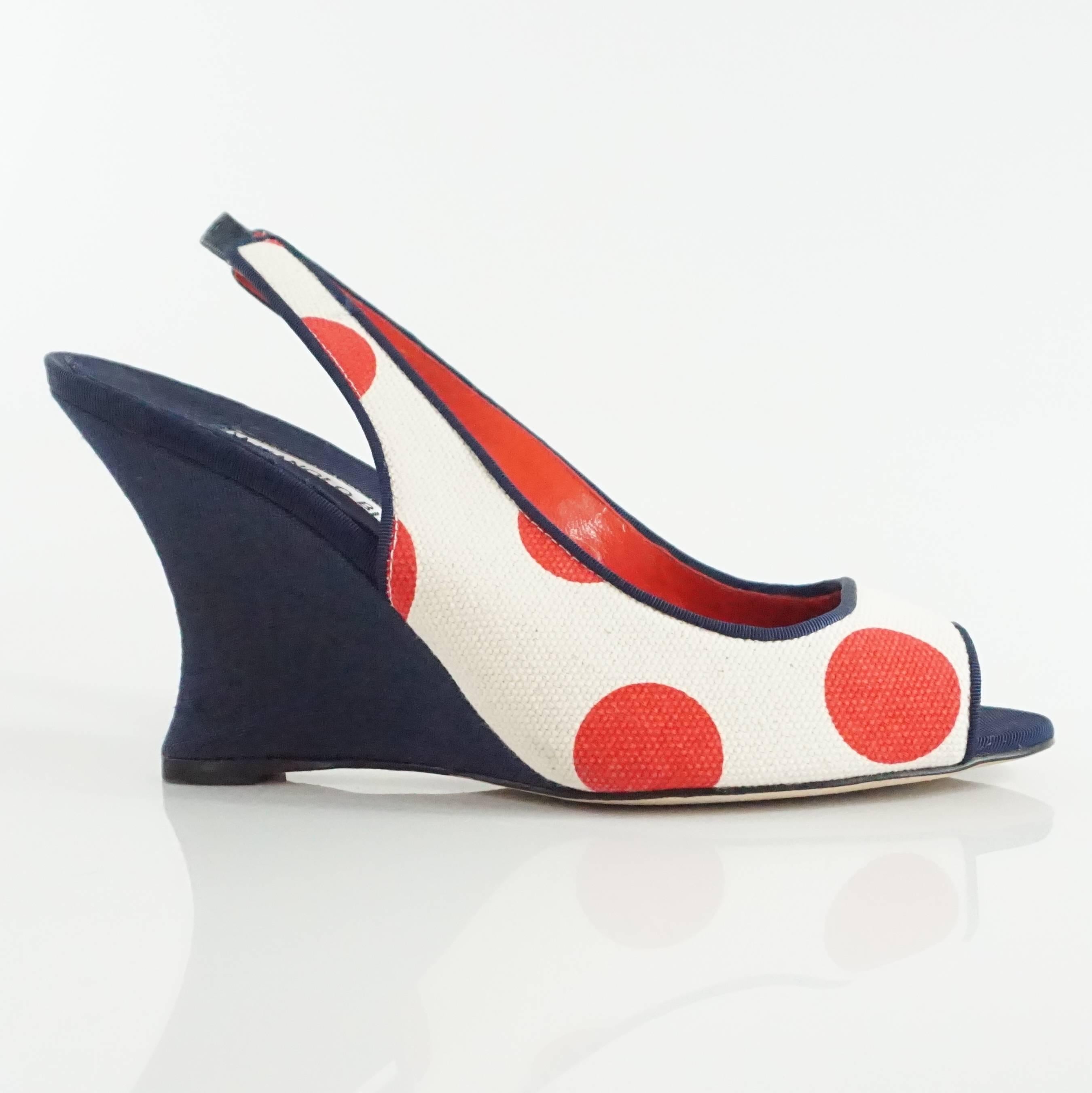 These Manolo Blahnik wedges are navy with a cream top. There are red polka dots and a navy trim. These wedges feature a peep toe and a slingback. They are in very good condition with very minor overall markings.

Measurements
Wedge Height: about