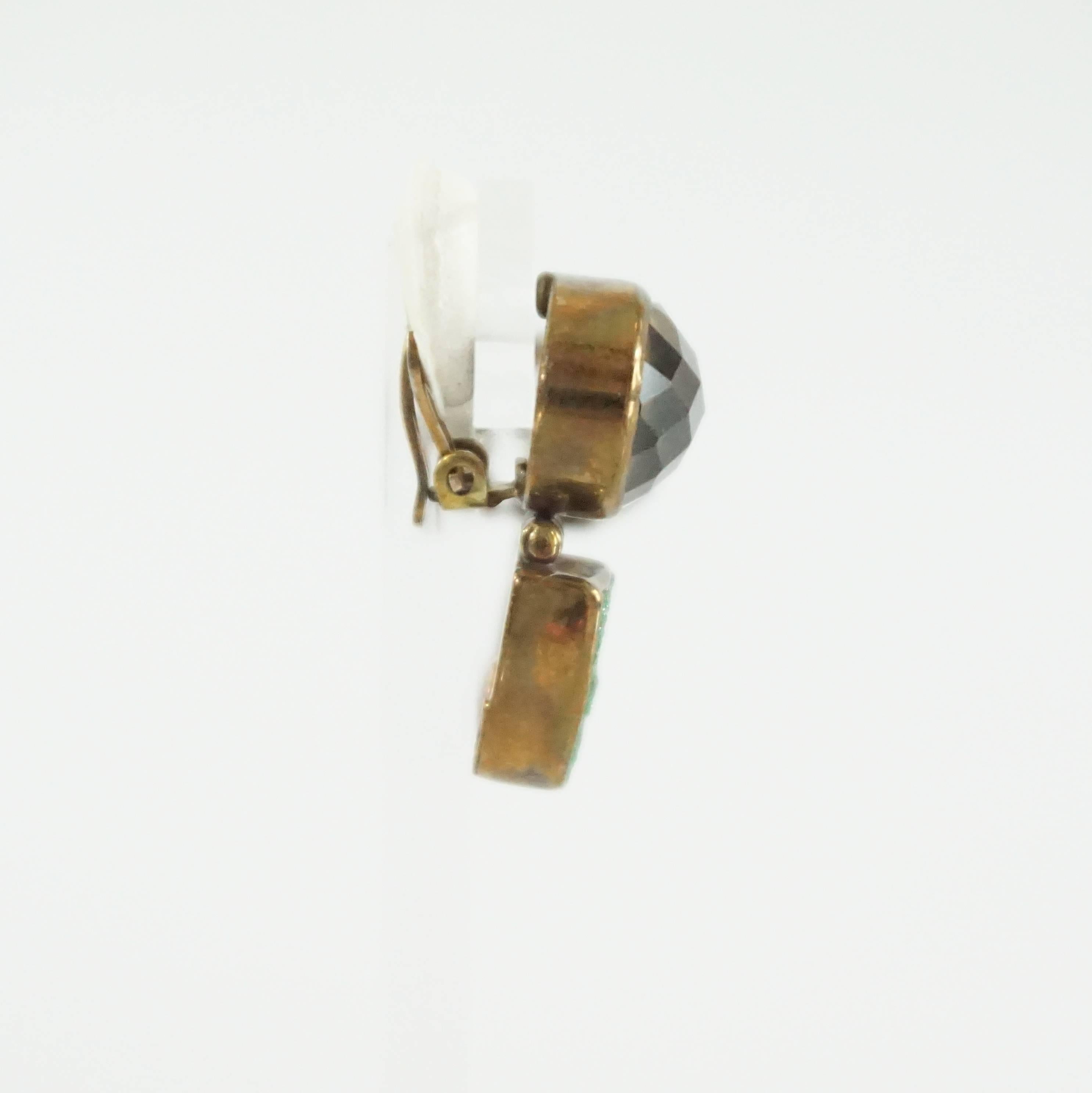 Stephen Dweck Smokey Quartz and Green Garnet  Bronze Earrings. These Stephen Dweck clip-on earrings feature a smoky quartz and a green garnet. The garnet has a druzy effect. There is a bronze trim and padding on the back. These earrings are in