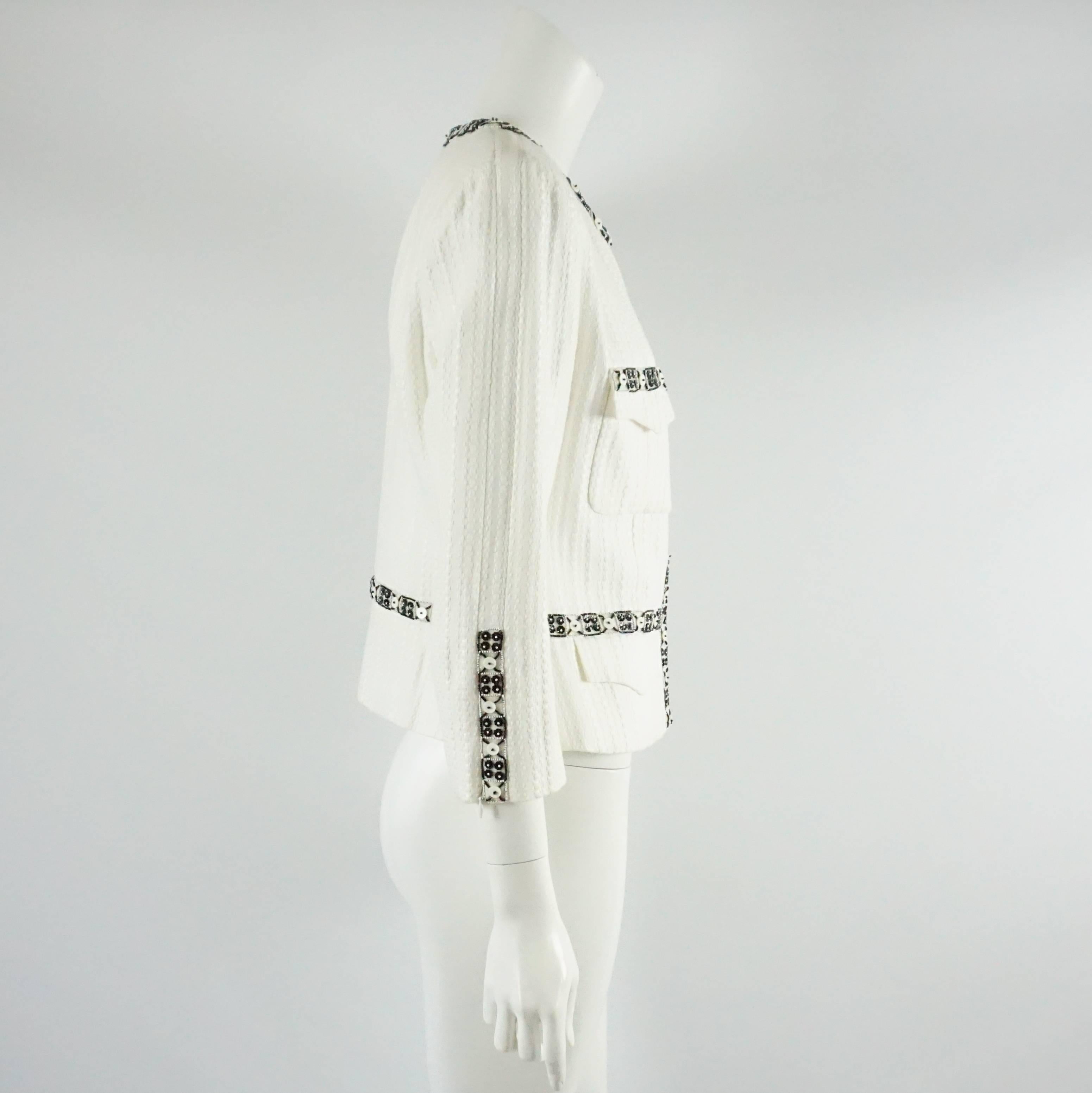 This Chanel white cotton jacket has a black beaded trim and detailing. There are 4 pockets on the front and a zipper on each sleeve cuff. This jacket is in excellent condition. Size 46.

Measurements
Shoulder to Shoulder: 15.5"
Sleeve Length: