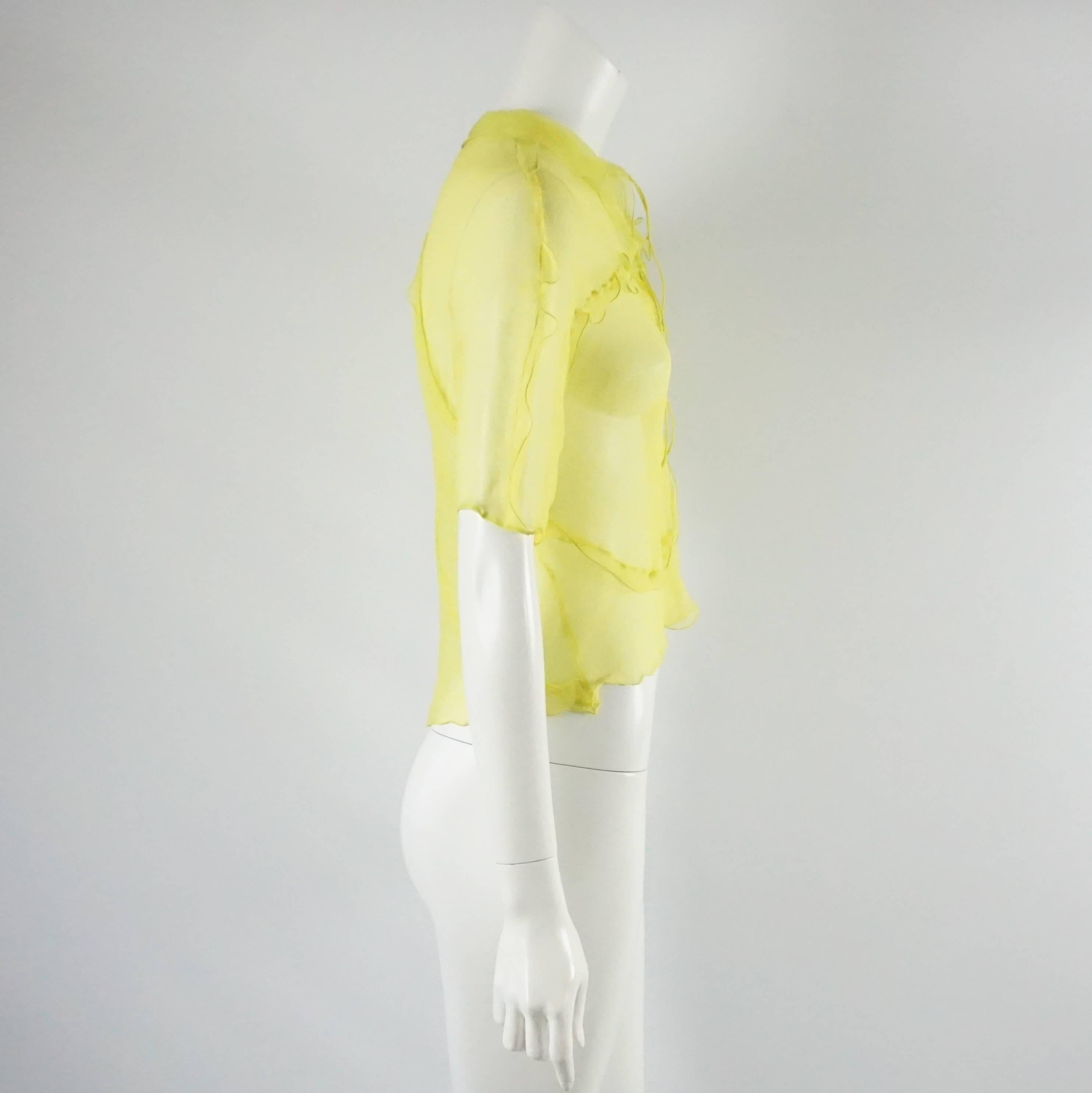 This Fendi top is yellow and silk chiffon. It has short sleeves and ruffles. There are two ties on the front that can be tied or untied and the fabric is stretchable. This top is in excellent condition. Size small.

Measurements
Sleeve Length