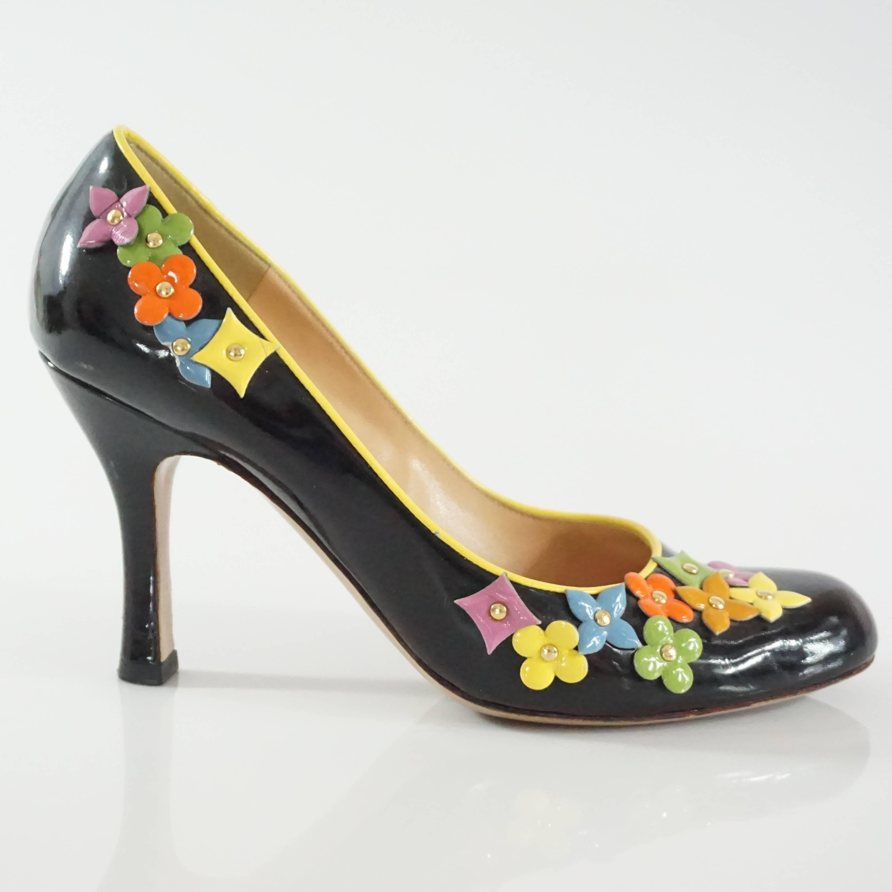 These Louis Vuitton black patent pumps have the signature multi color flowers all over with a yellow trim. They are in fair condition with some wear on the patent and one piece of the flower missing as indicated by the images. Size 36.
