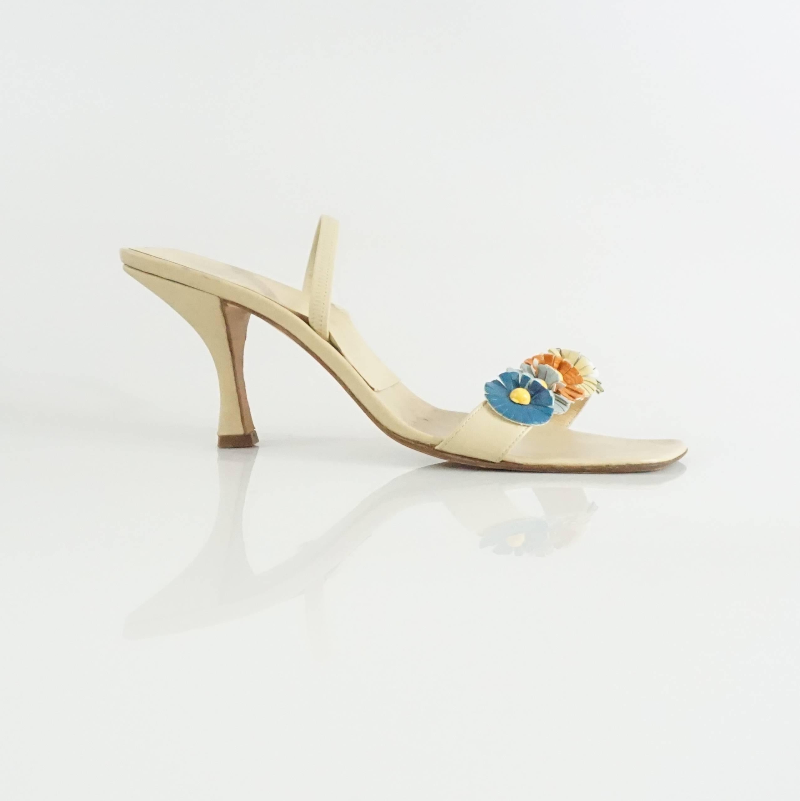 These Fendi sandals are beige leather with five multi colored leather flowers with yellow centers on the toe strap. There is another strap to help keep the sandal on and an angular toe bed. These shoes are in good condition with minor wear on the