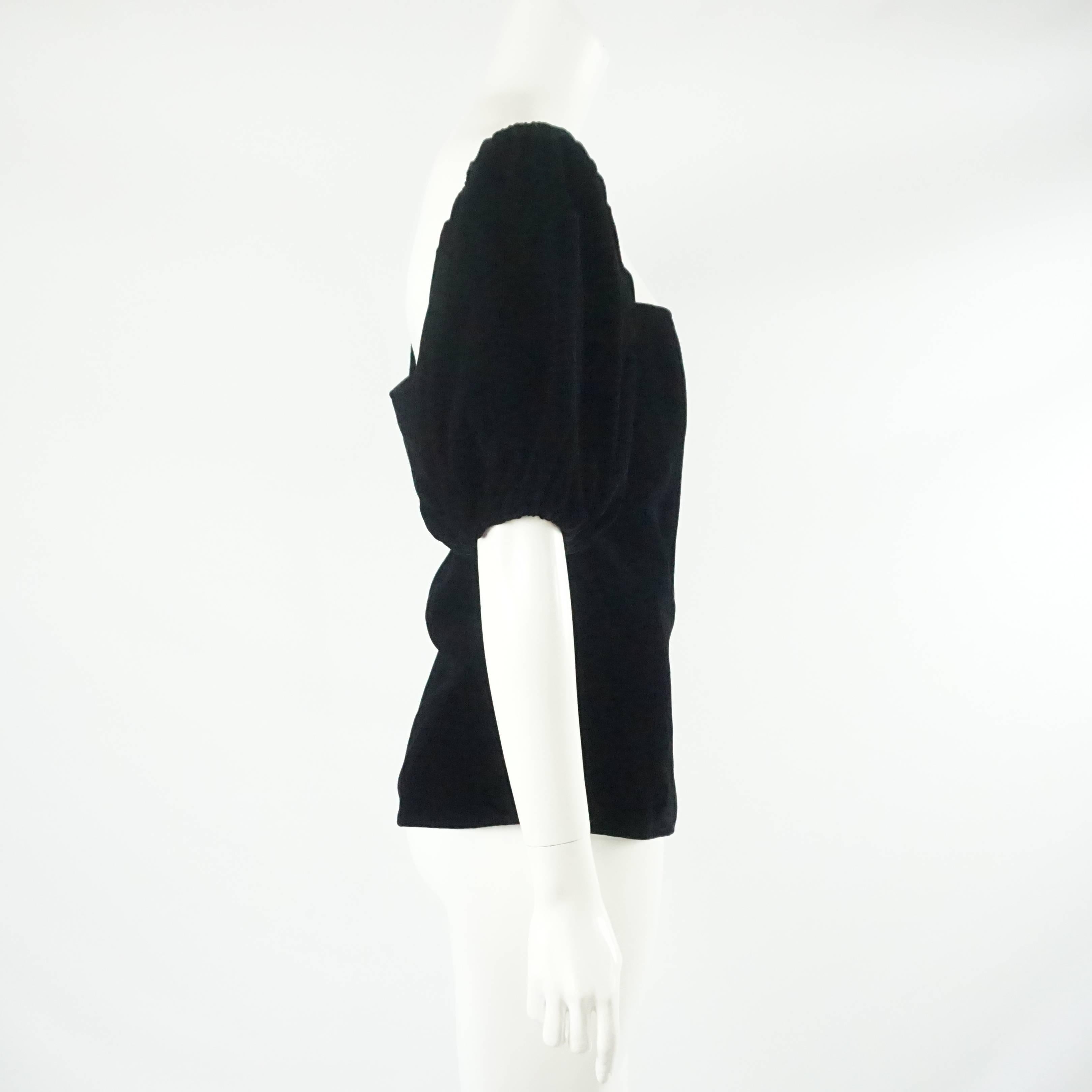 This vintage YSL black velvet top has a straight neckline with puffed elbow length sleeves. The blouse falls mid-back and has a back zipper. It is in fair vintage condition due to inside wear and pressing in the velvet as seen in the last images.
