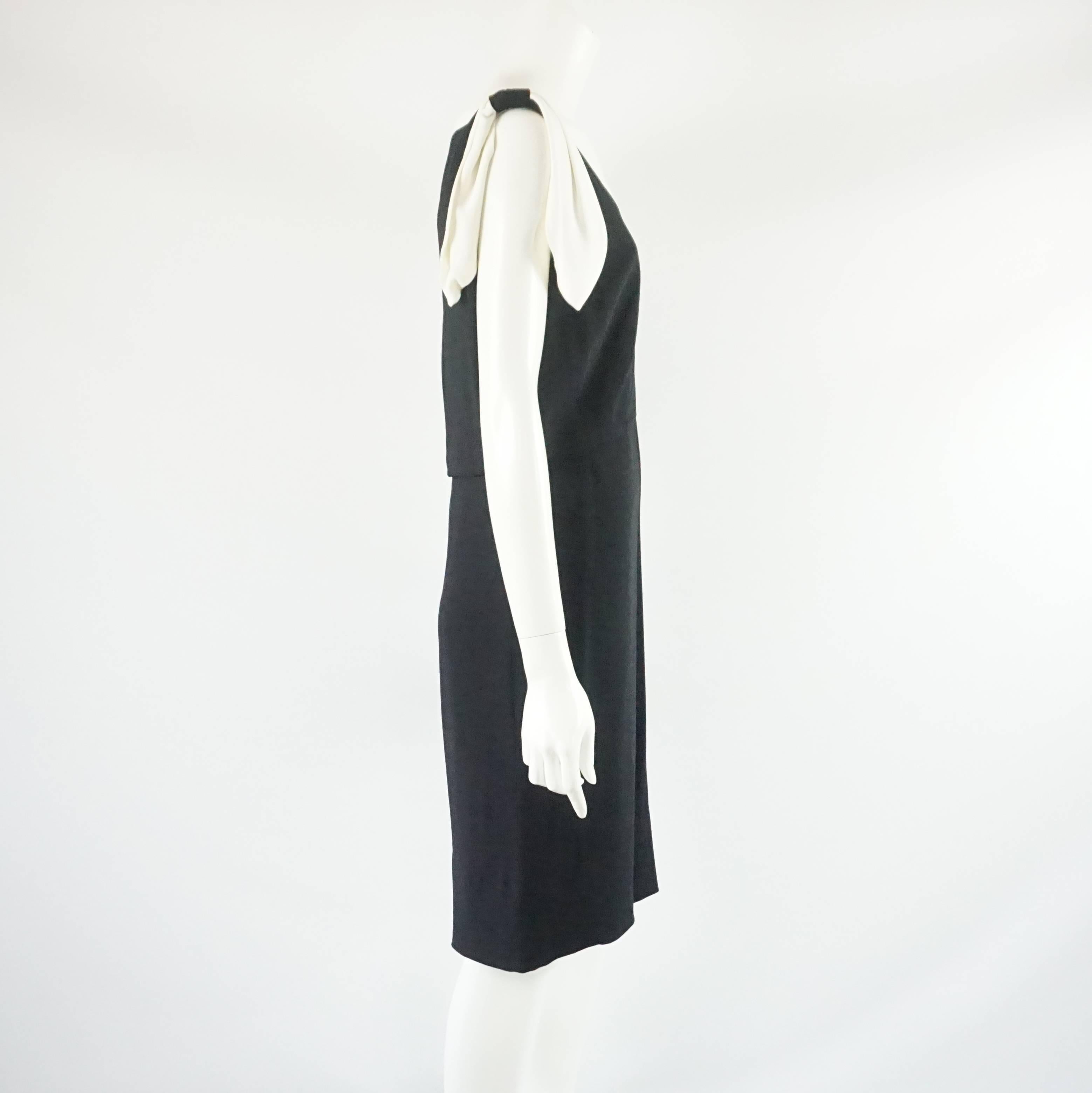 This Valentino wool blend dress is a timeless piece. The black dress is sleeveless with an ivory trim along the neckline and a hanging bow on each side.  It also has a v-neck and zips in the back. The dress is in good condition with a few minor