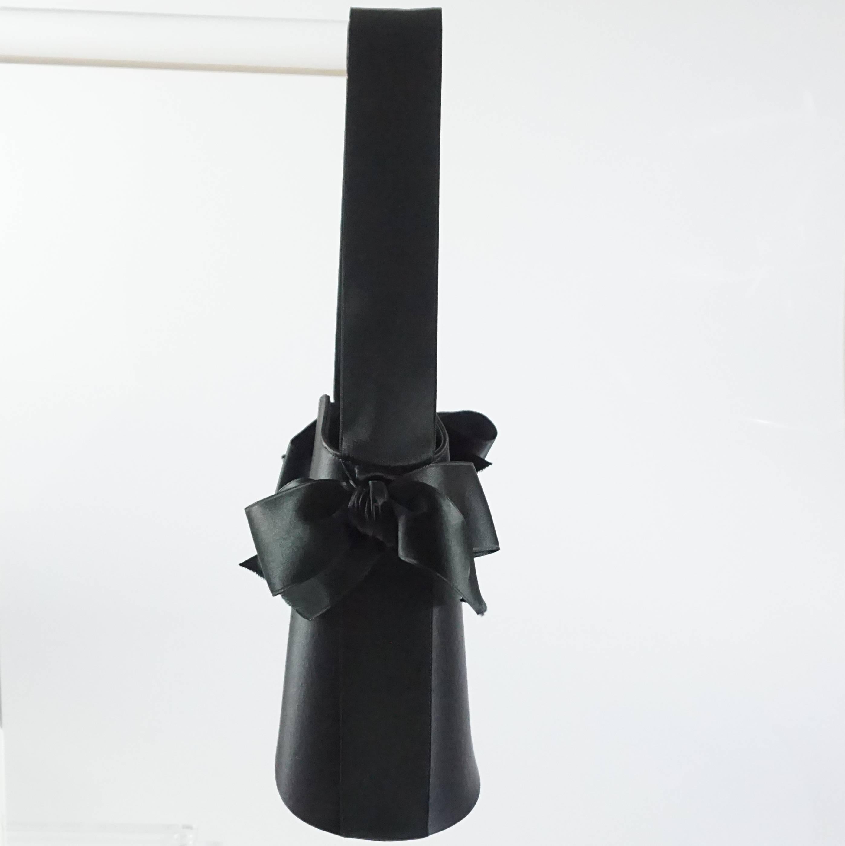 This Renaud Pellegrino top handle bag is made of beautiful black satin. It features a ribbon handle and two ribbon bows. Inside there is a pocket. This bag is in excellent condition.

Measurements
Height: 7” – 7 5/8” 
Width: 5 7/8”
Depth: 4”
Handle