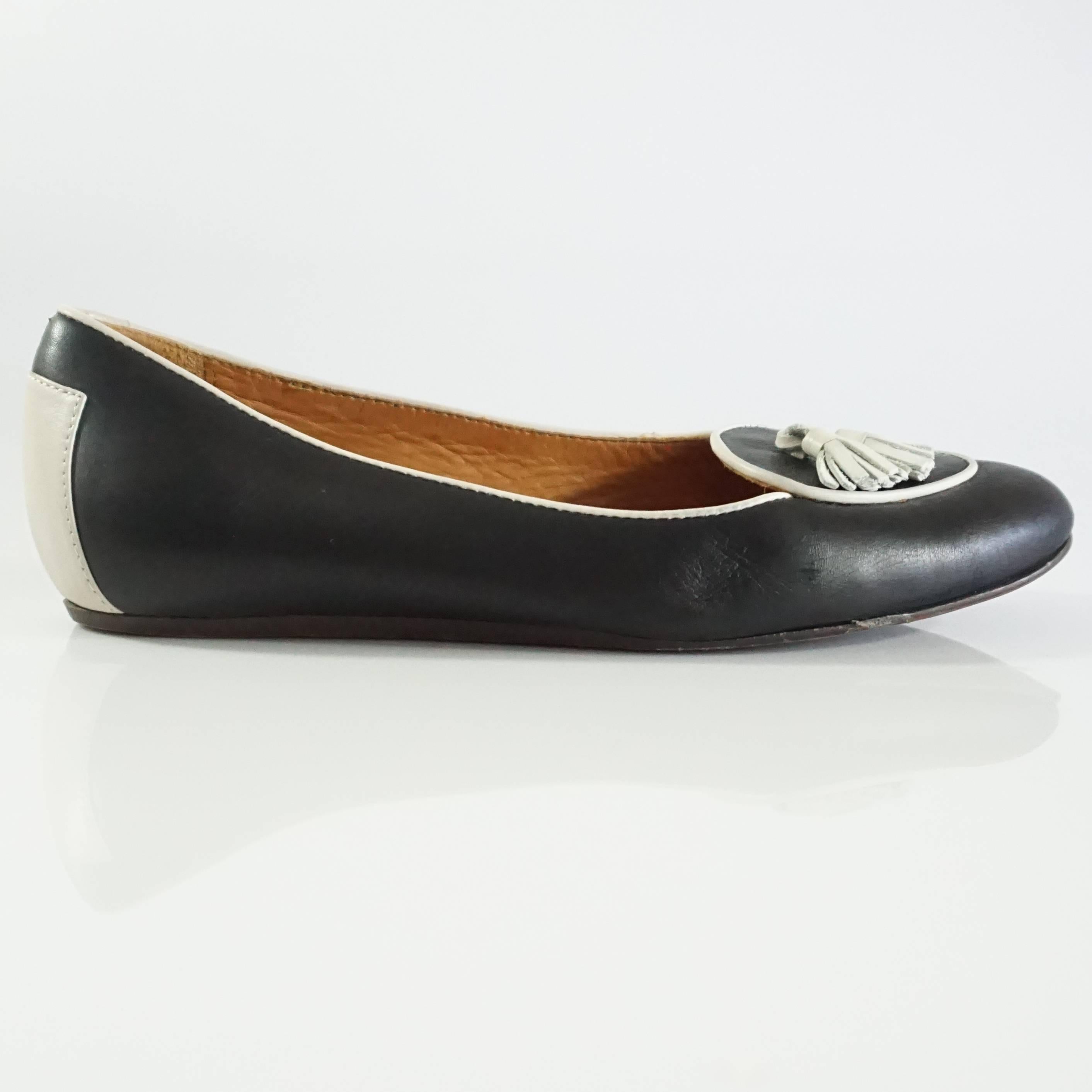 These Lanvin loafers are black leather with ivory trim. They feature ivory tassels on the toes. These shoes are in very good condition with minor bottom wear and overall wear. Size 37.5.
