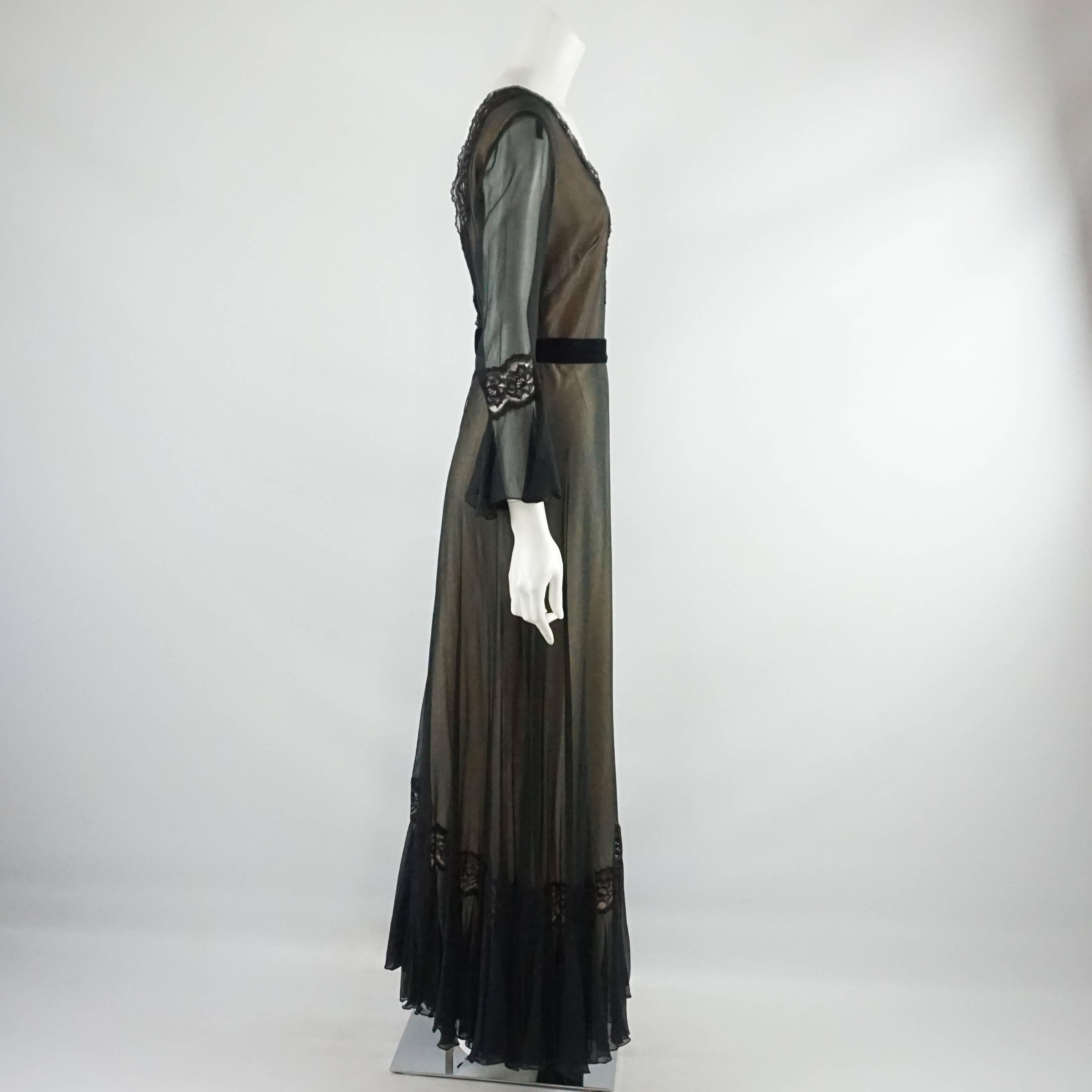 This Jean Allen gown is long sleeved with a v-neck. It is silk with a lacy trim on the neck and sheer sleeves. There is a waist band and lace detailing on the sleeves. This gown is in excellent condition. Size small, circa late