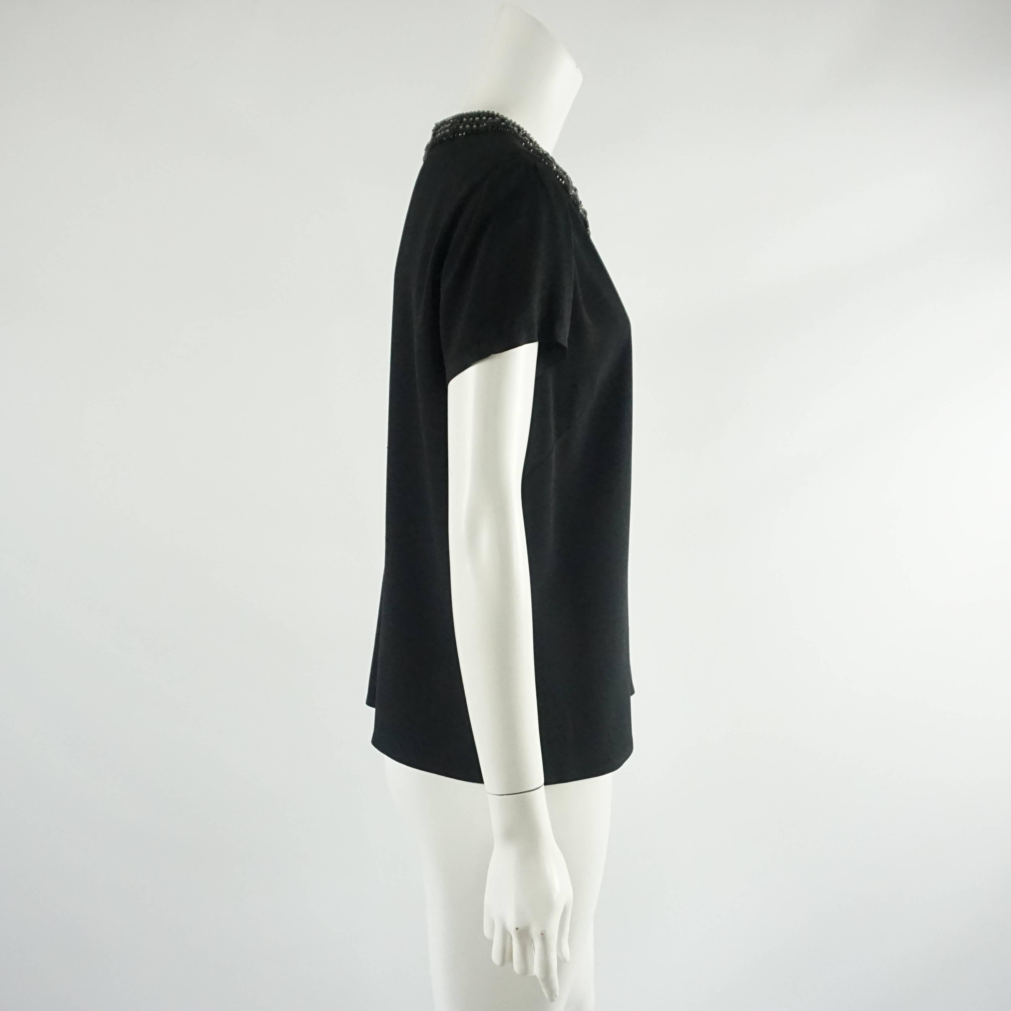 This Ralph Lauren Black Label top is short sleeved. It has a heavily beaded neckline. This top is in excellent condition. Size 10.

Measurements
Shoulder to Shoulder: 16.25