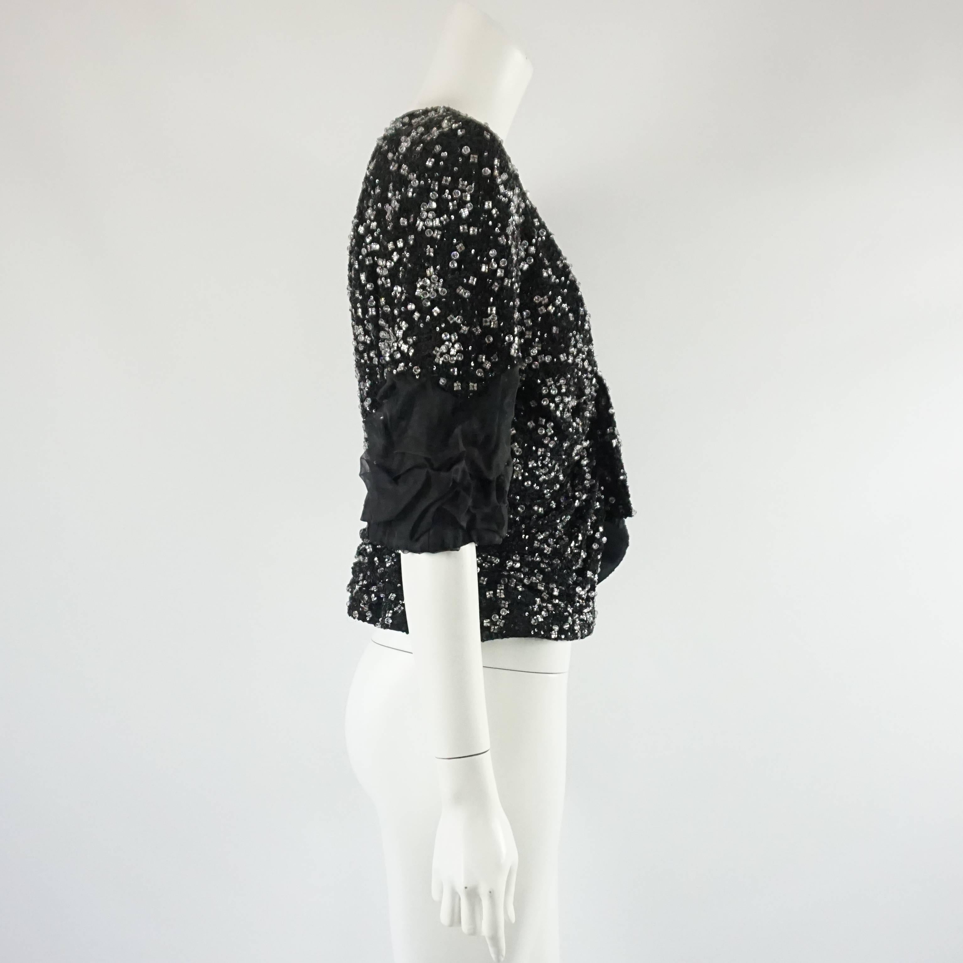 This stunning Giorgio Armani beaded jacket can also be worn as a top and has shoulder pads. The piece is made of silk and covered with small black sequins and embroidered on top with clear rhinestone beads. The sleeves fall at the elbows and have a